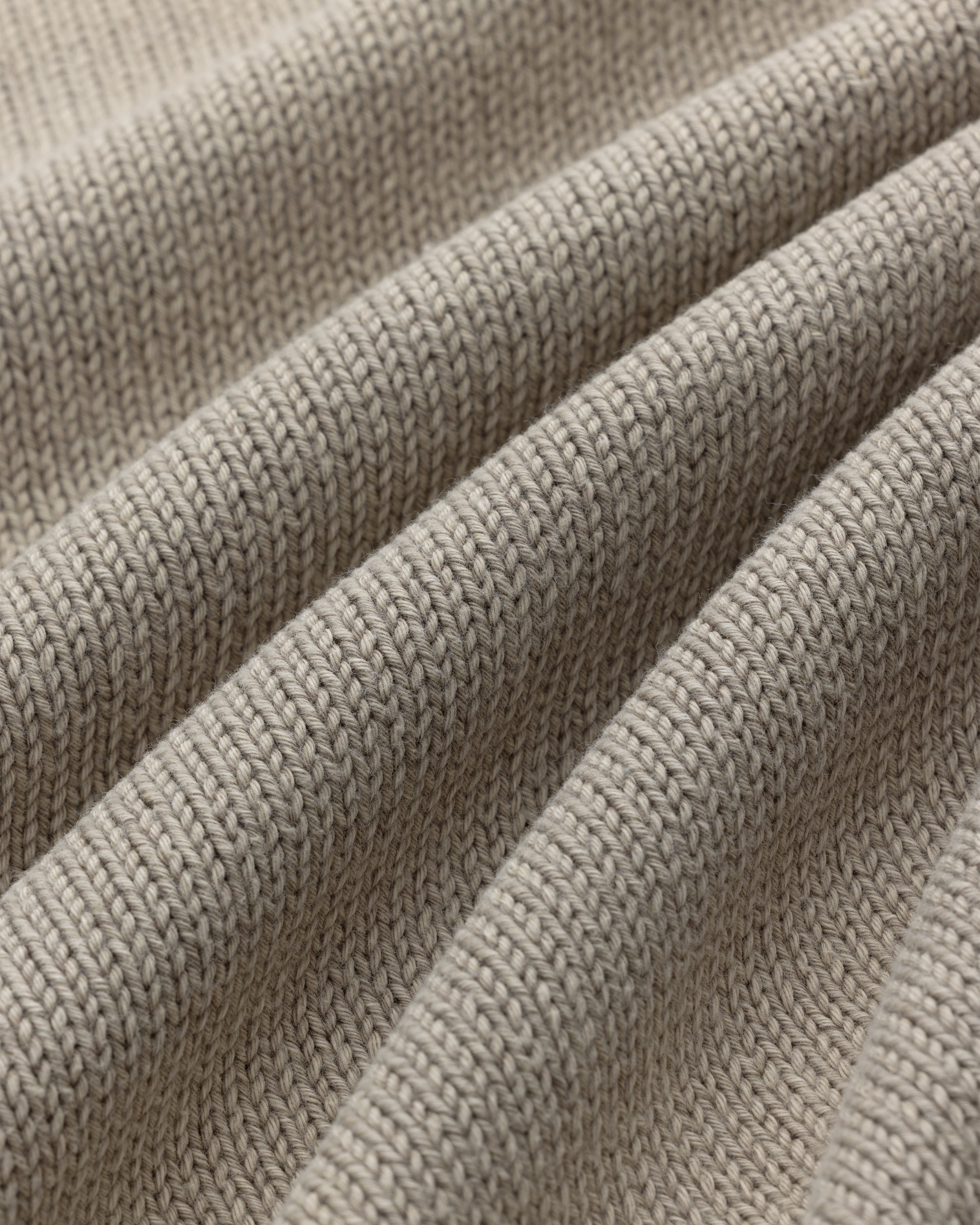 Close-up of Washed Inside Out Sweater in beige, showing textured knit stitches and gentle folds.