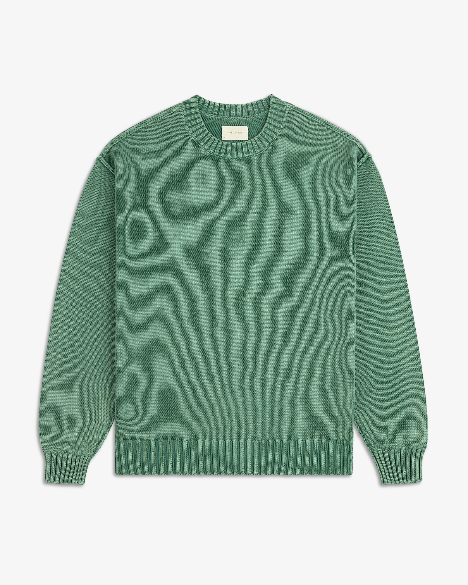 The Washed Inside Out Sweater is a plain green, long-sleeve crew-neck with ribbed cuffs, collar, and hem on white background.