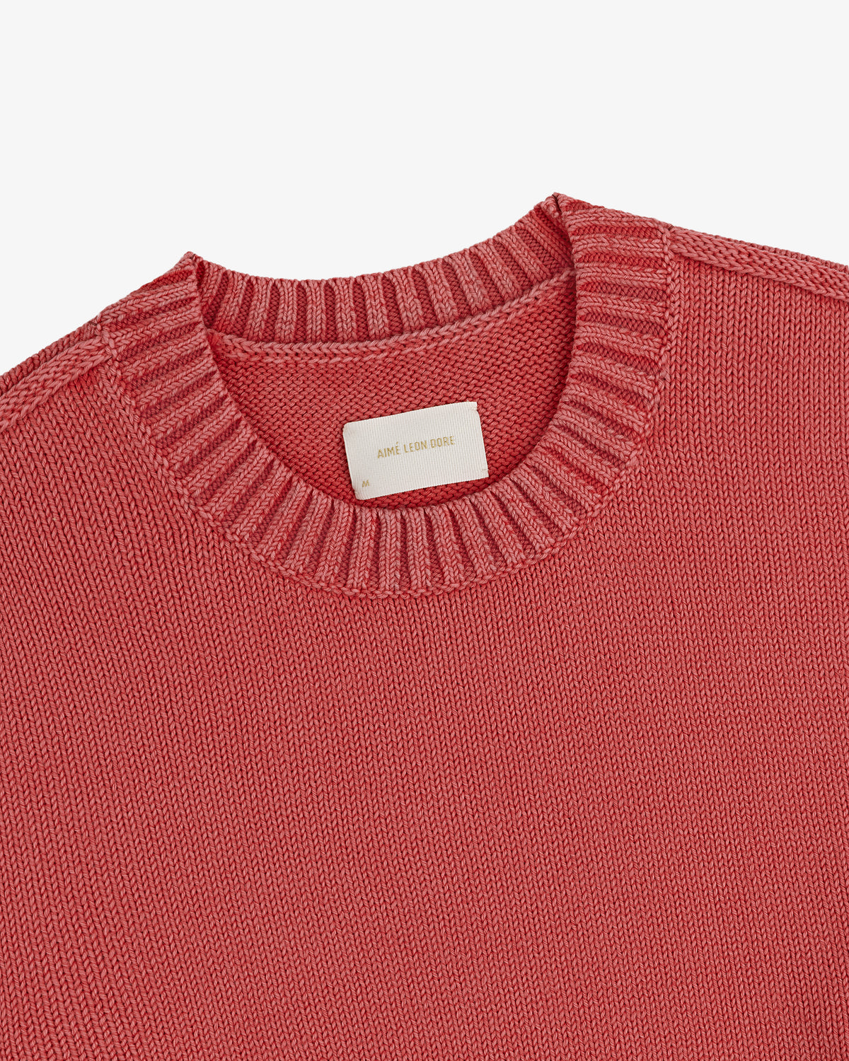 A close-up of the Washed Inside Out Sweater, pink with a crewneck, visible collar, and blank white label inside.