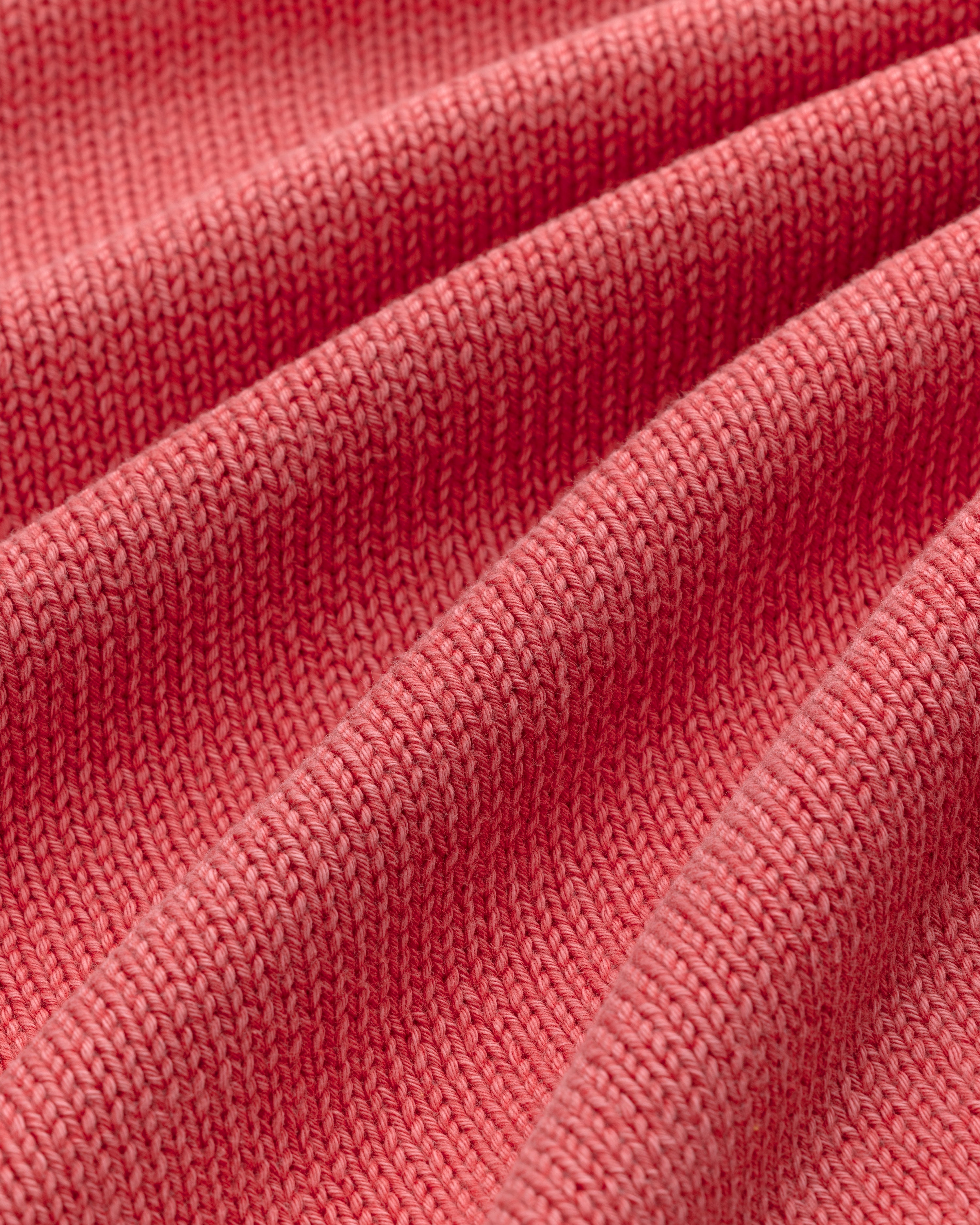 Close-up of the Washed Inside Out Sweater's ribbed pink knit fabric, showing its texture and soft folds.