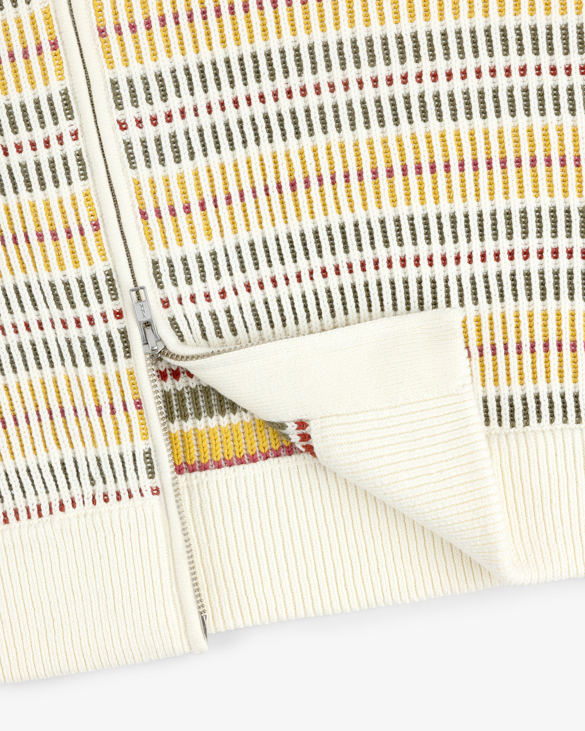 Close-up of the Multi Color Knit Track Sweater featuring a cream zip-up style with vertical yellow, olive, and red stripes.