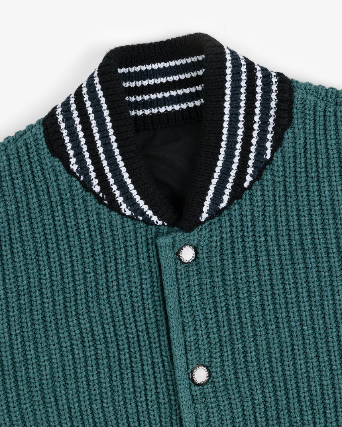 Close-up of the Reversible Knit Bomber Jacket with green texture, silver buttons, and a black collar with white stripes.