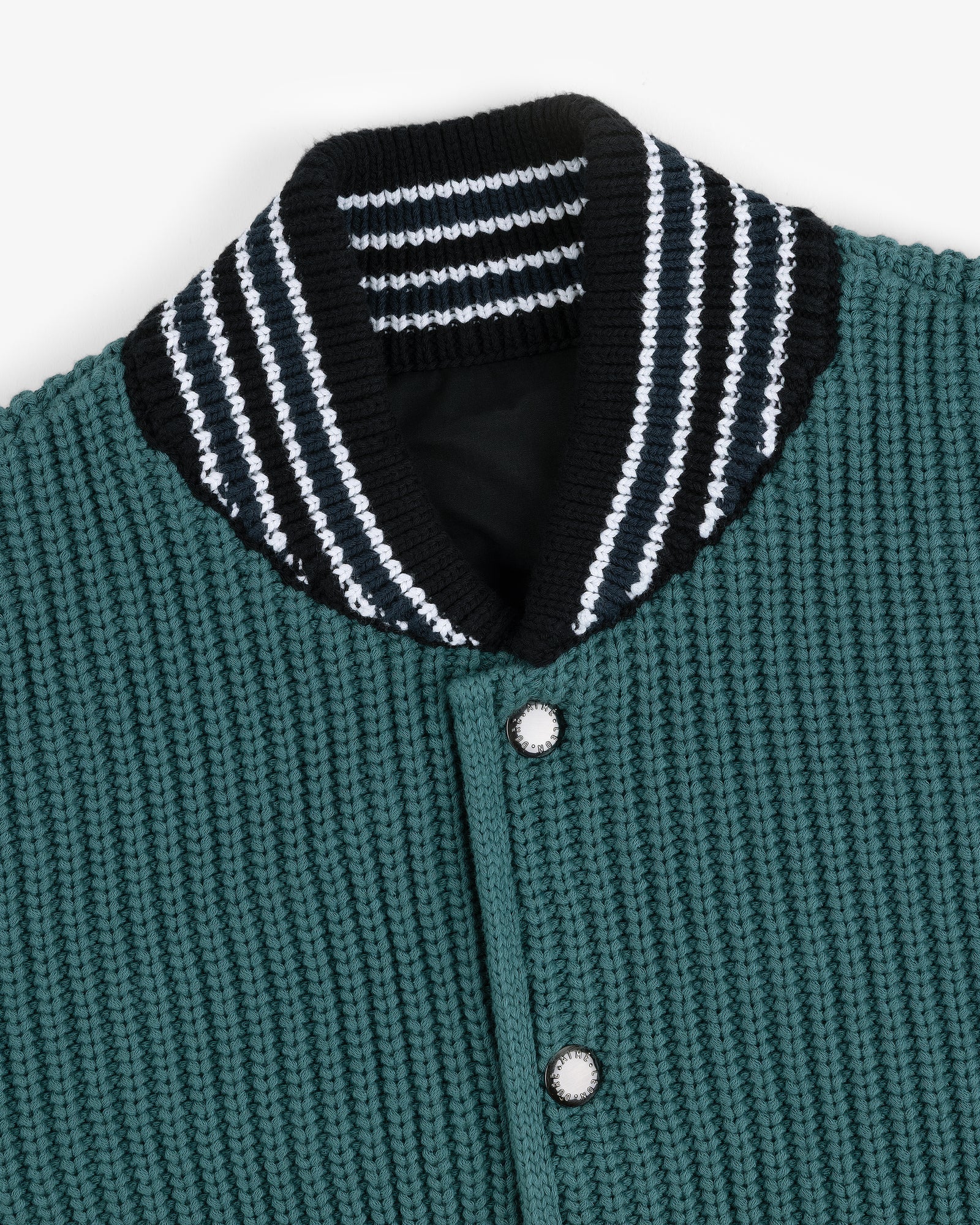 Close-up of the Reversible Knit Bomber Jacket with green texture, silver buttons, and a black collar with white stripes.