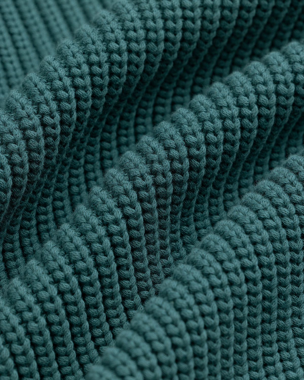 Close-up of textured, teal Reversible Knit Bomber Jacket featuring thick ridges and detailed stitching.