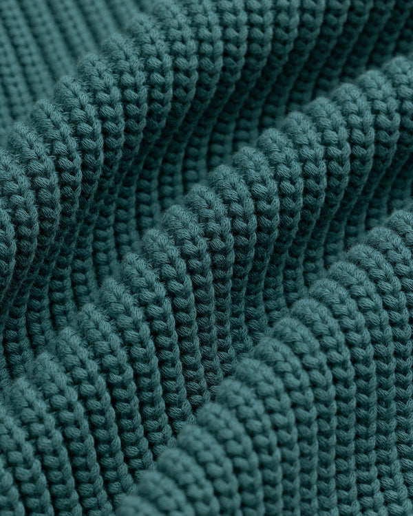 Close-up of textured, teal Reversible Knit Bomber Jacket featuring thick ridges and detailed stitching.