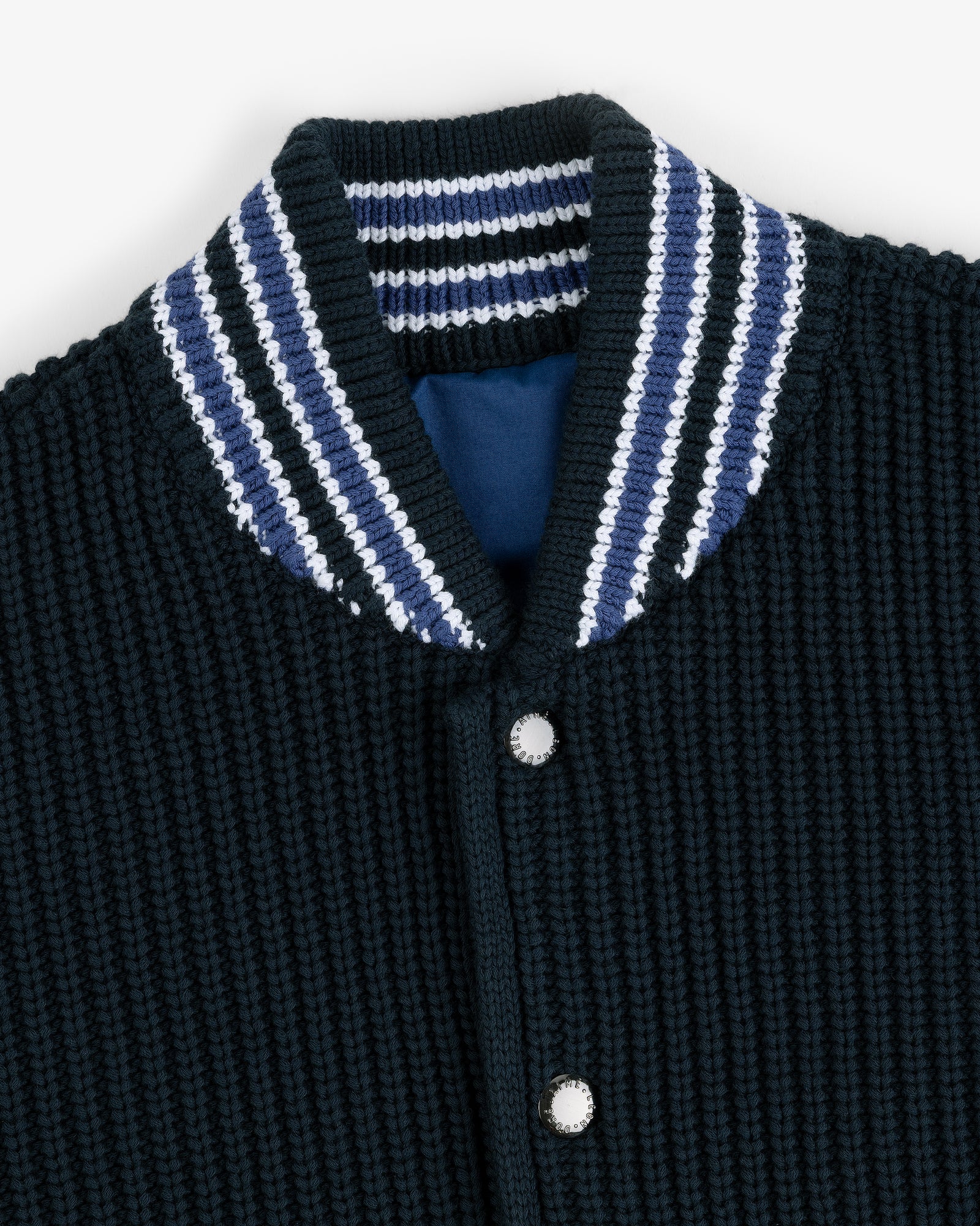 Close-up of a Reversible Knit Bomber Jacket with a textured black finish, striped collar, and silver snap buttons.