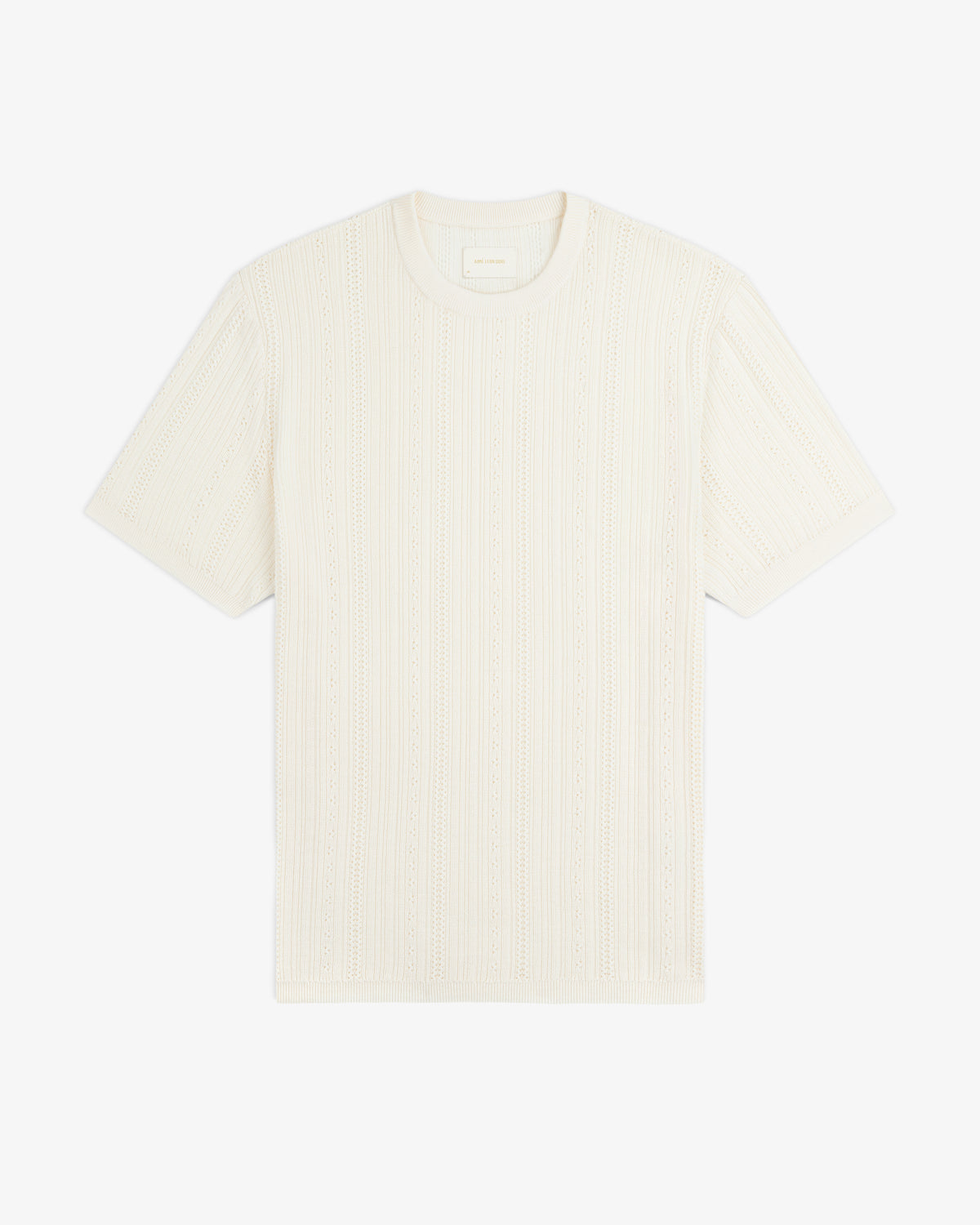 The Merino Wool Eyelet Tee is a short-sleeve, cream knit T-shirt with a subtle textured pattern, shown flat on white.