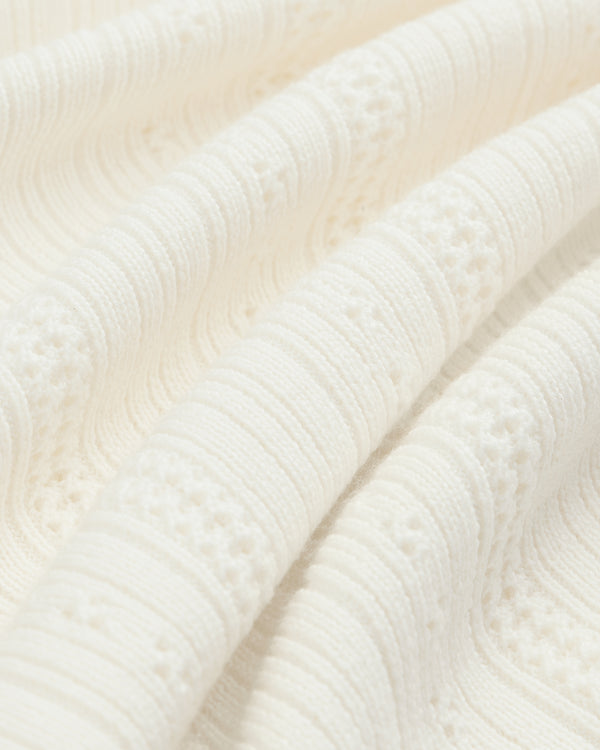 Close-up of textured Merino Wool Eyelet Tee featuring off-white raised, wavy knit patterns and intricate details.
