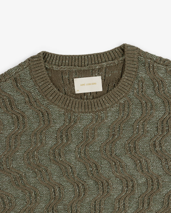 Olive green Linen Blend Cable Knit Sweater with a wavy pattern and Aimé Leon Dore label at the neckline.