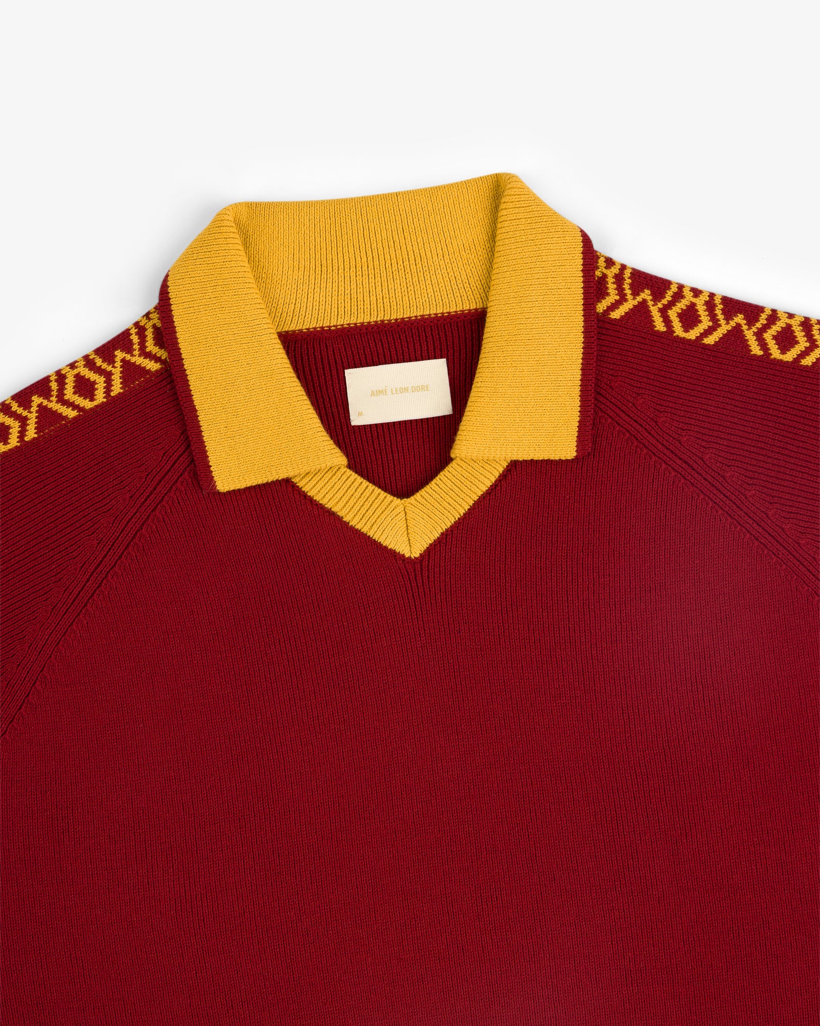 Knit Sport Pullover in maroon with a gold collar and gold patterned shoulder detailing.