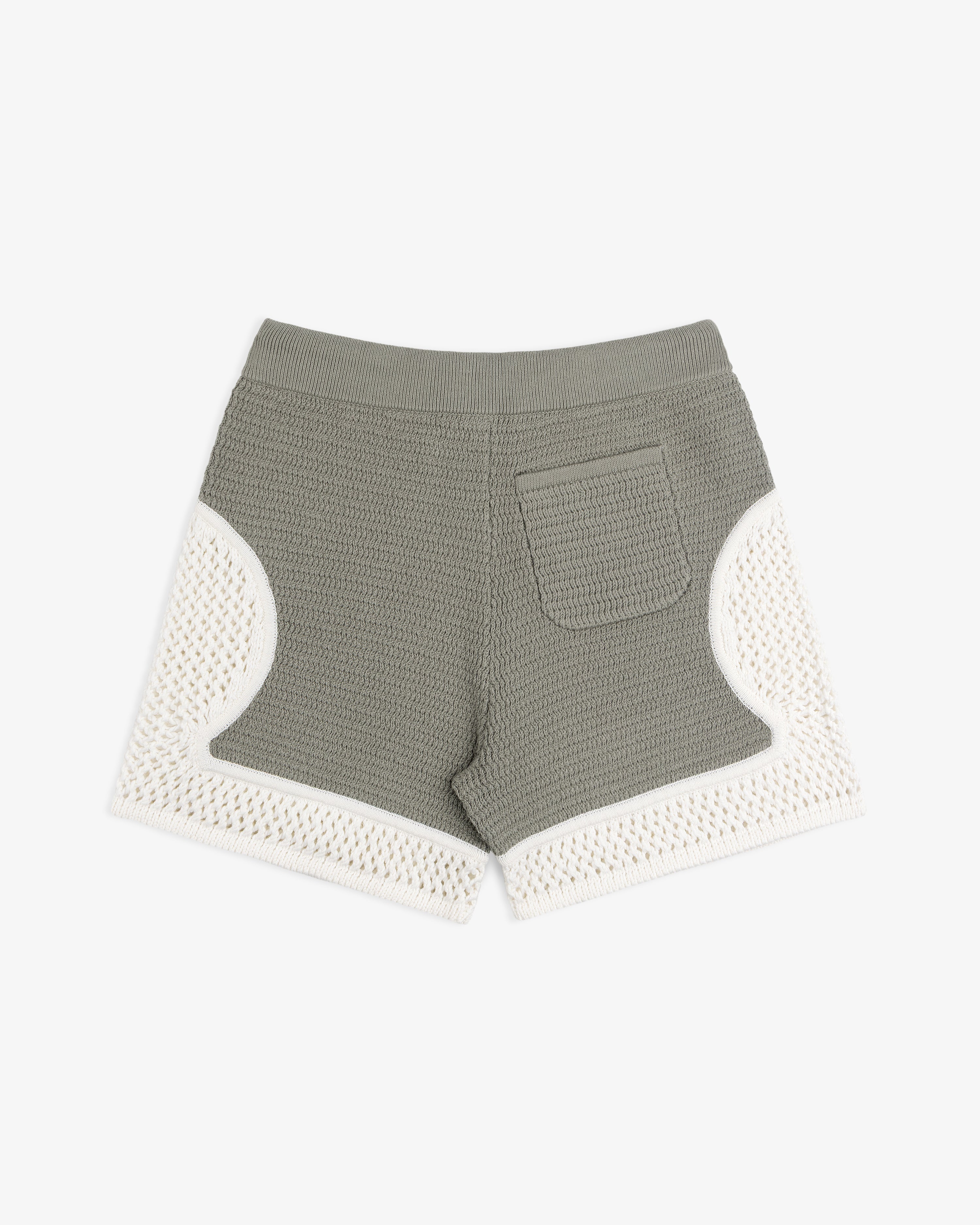 Knit Court Short in green with a back pocket and white crochet trim on sides and hem, shown on a white background.