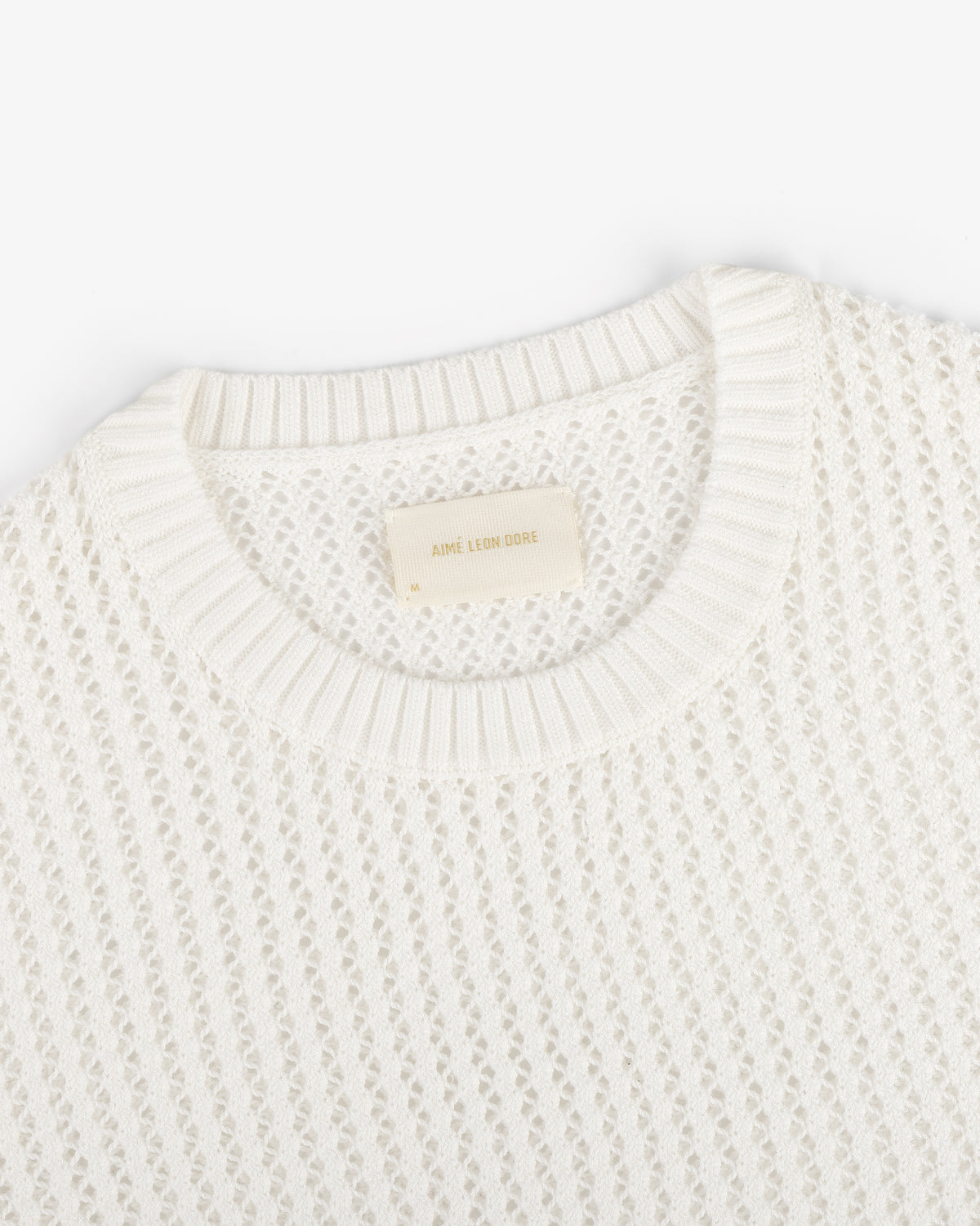 Fassianos "Rendez-Vous" Crewneck Sweater—white knit with open weave, ribbed neckline, and beige Aimé Leon Dore label.