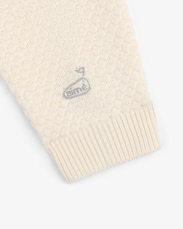 Close-up of the ALD Golf Clubhouse Sweater sleeve featuring a small embroidered logo near the cuff.