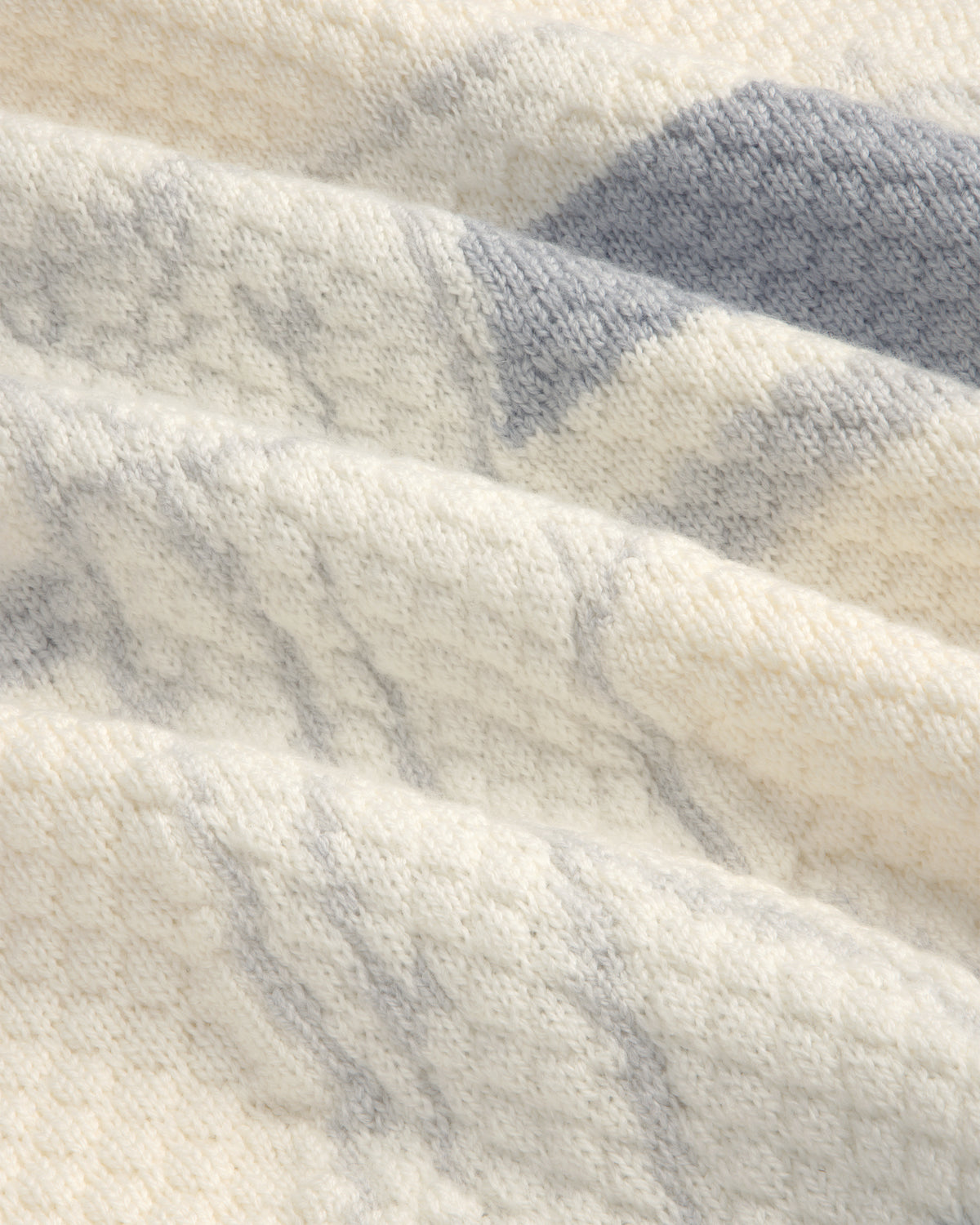 Close-up of the ALD Golf Clubhouse Sweater’s soft, cream fabric with gray diagonal stripes and a textured surface.