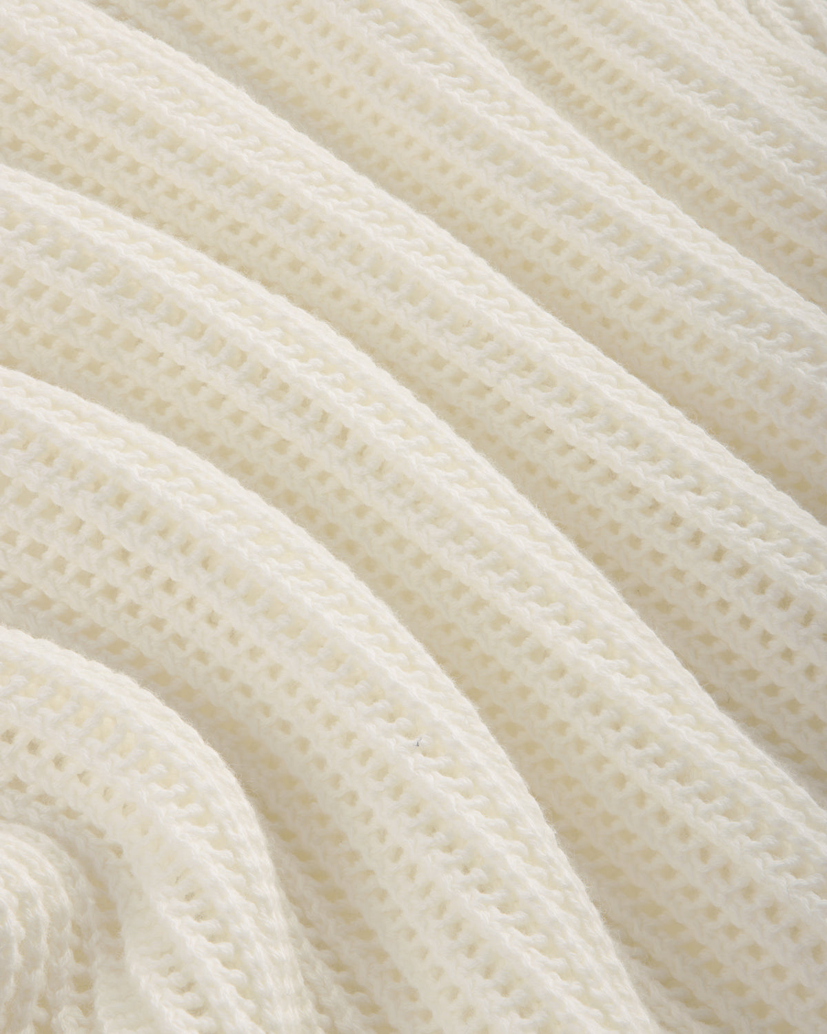 Close-up of the Mesh Knit Polo's soft, white ribbed fabric with a wavy, textured pattern.