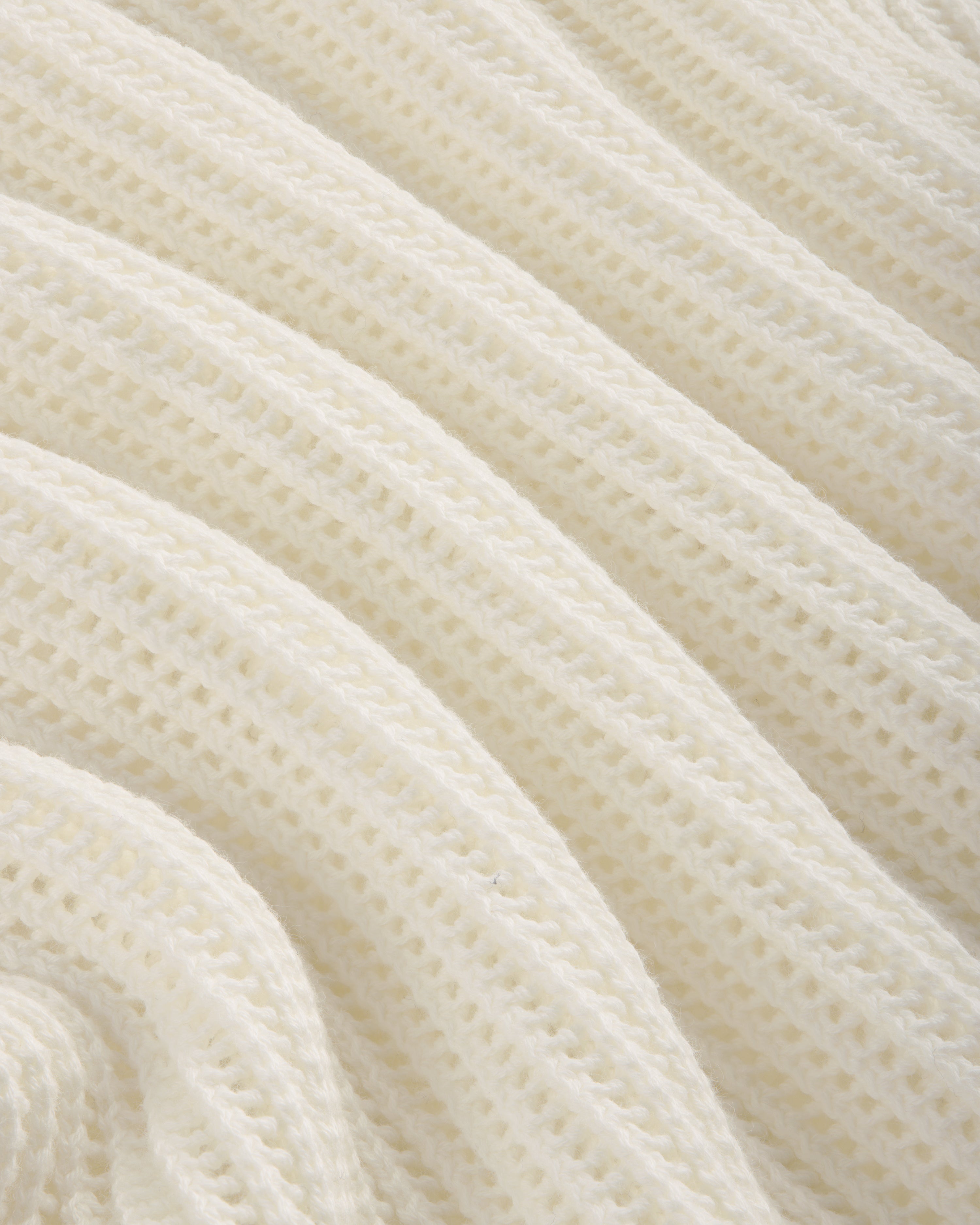 Close-up of the Mesh Knit Polo's soft, white ribbed fabric with a wavy, textured pattern.