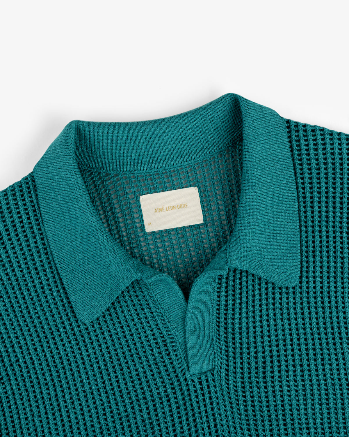 Teal Mesh Knit Polo with a textured pattern, partial button front, and visible beige label inside the collar.