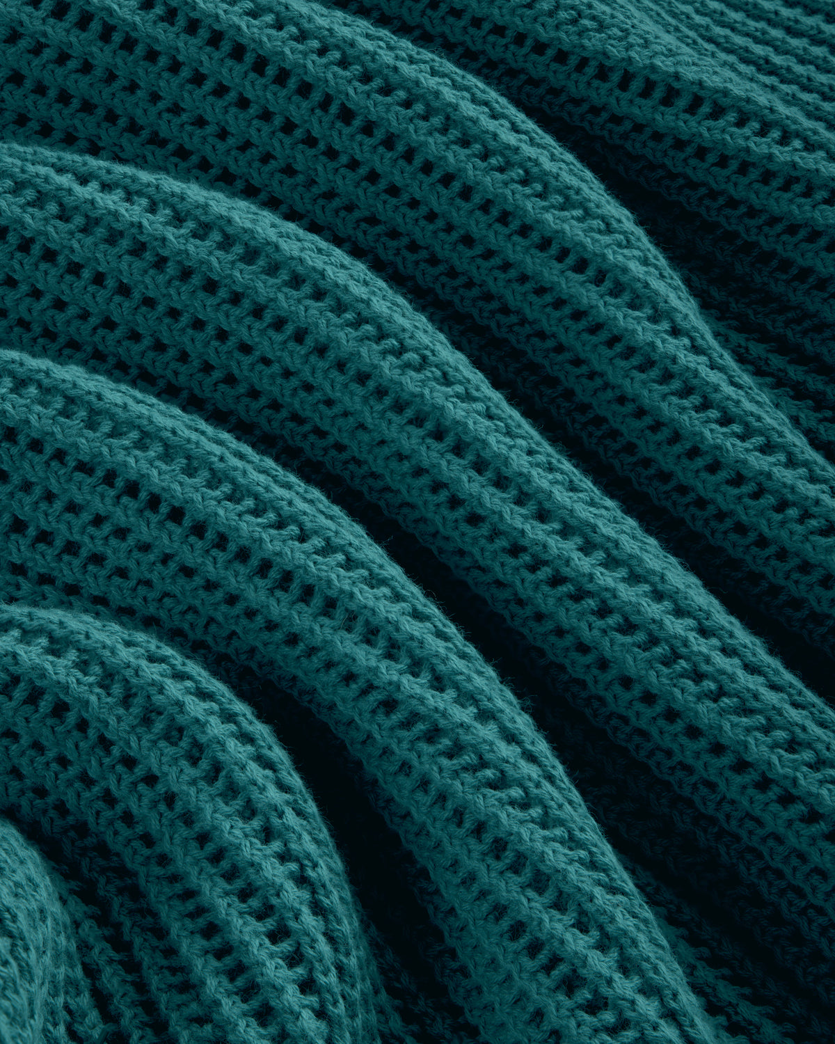 Close-up of the Mesh Knit Polo in teal, featuring a textured, wavy knit pattern with ridges and rows.