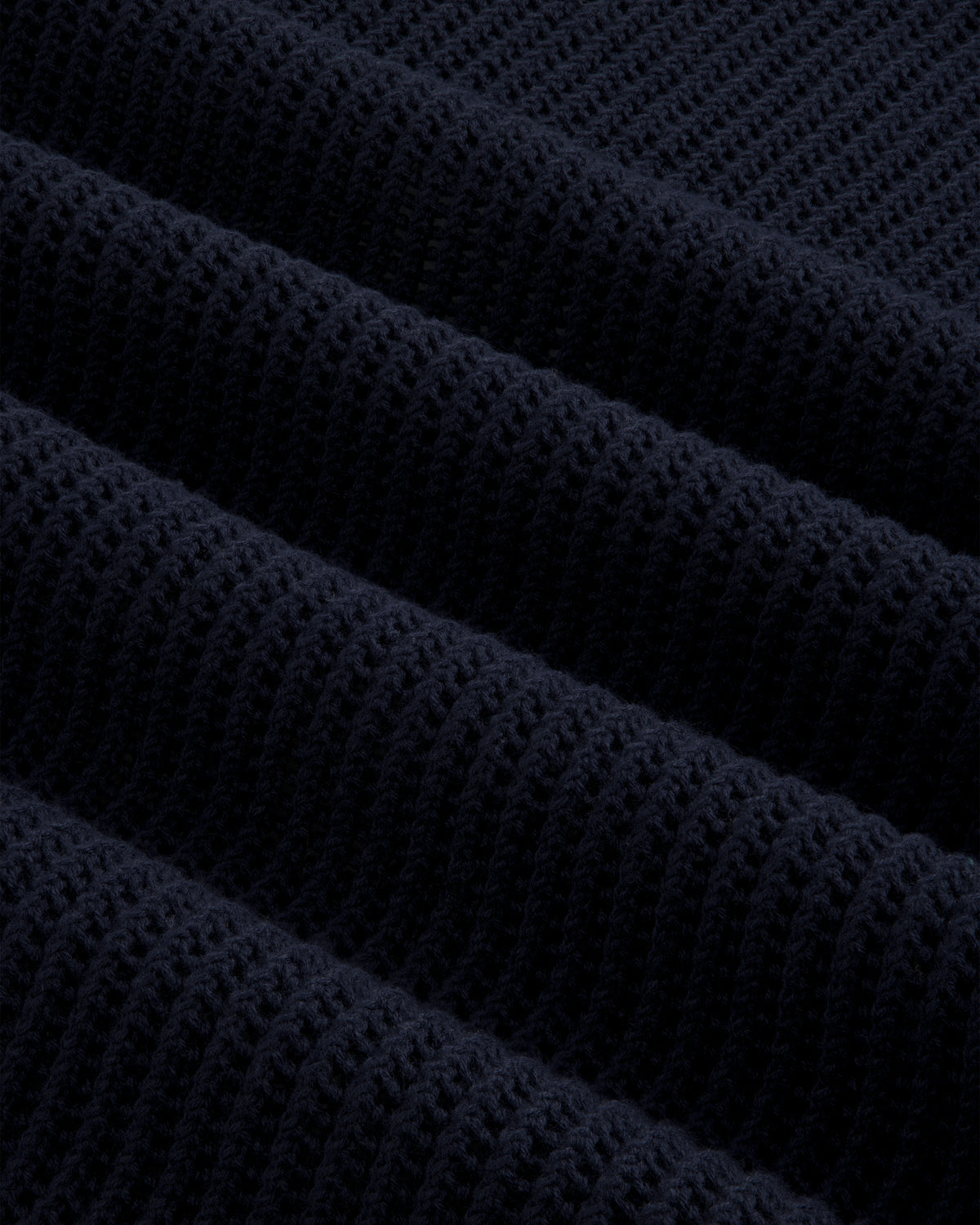 Close-up of dark blue Mesh Knit Polo, highlighting ribbed texture with horizontal ridges and soft material detail.