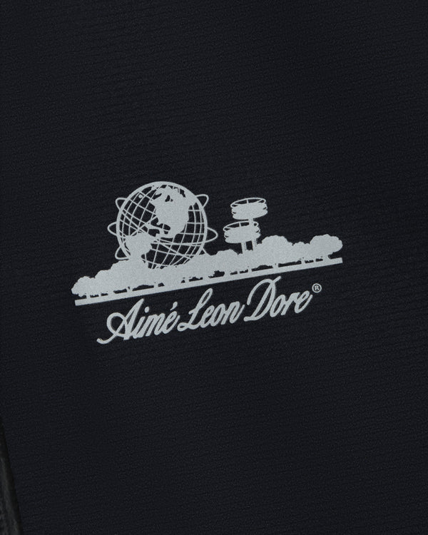 White Aimé Leon Dore logo with globe, trees, and buildings on the Lightweight GORE-TEX Shell Jacket.