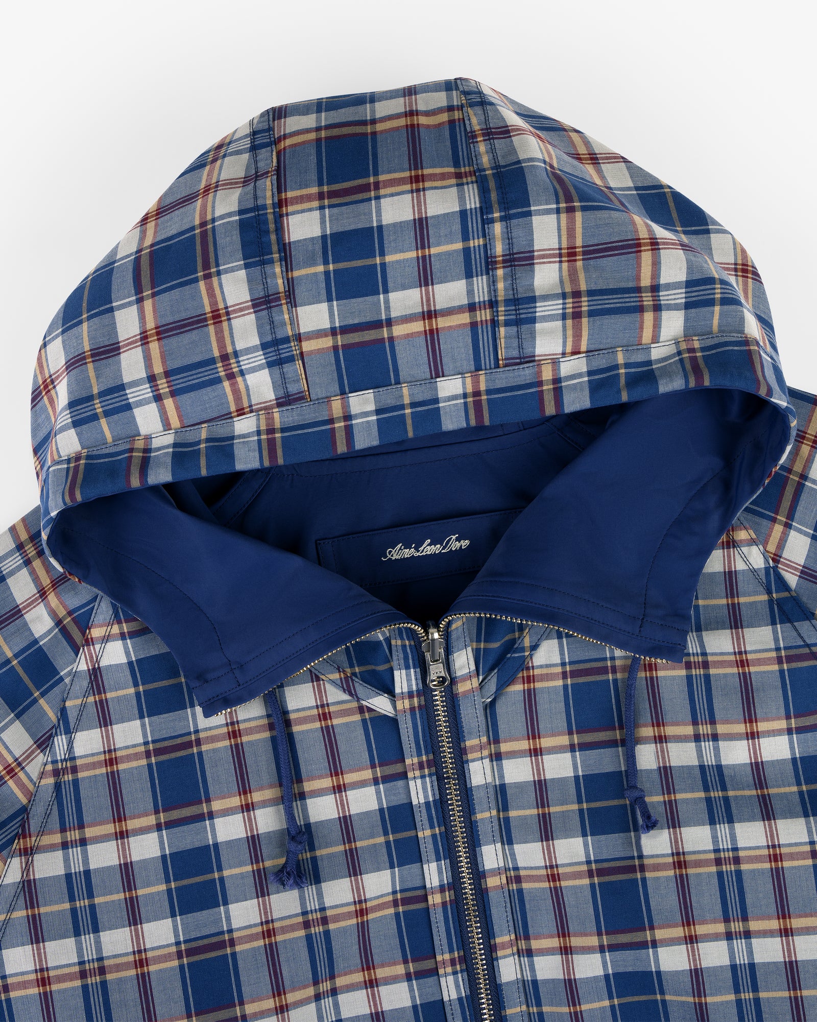 Reversible Madras Windbreaker in blue, white, and red plaid with hood, zipper, and solid blue lining, top view.