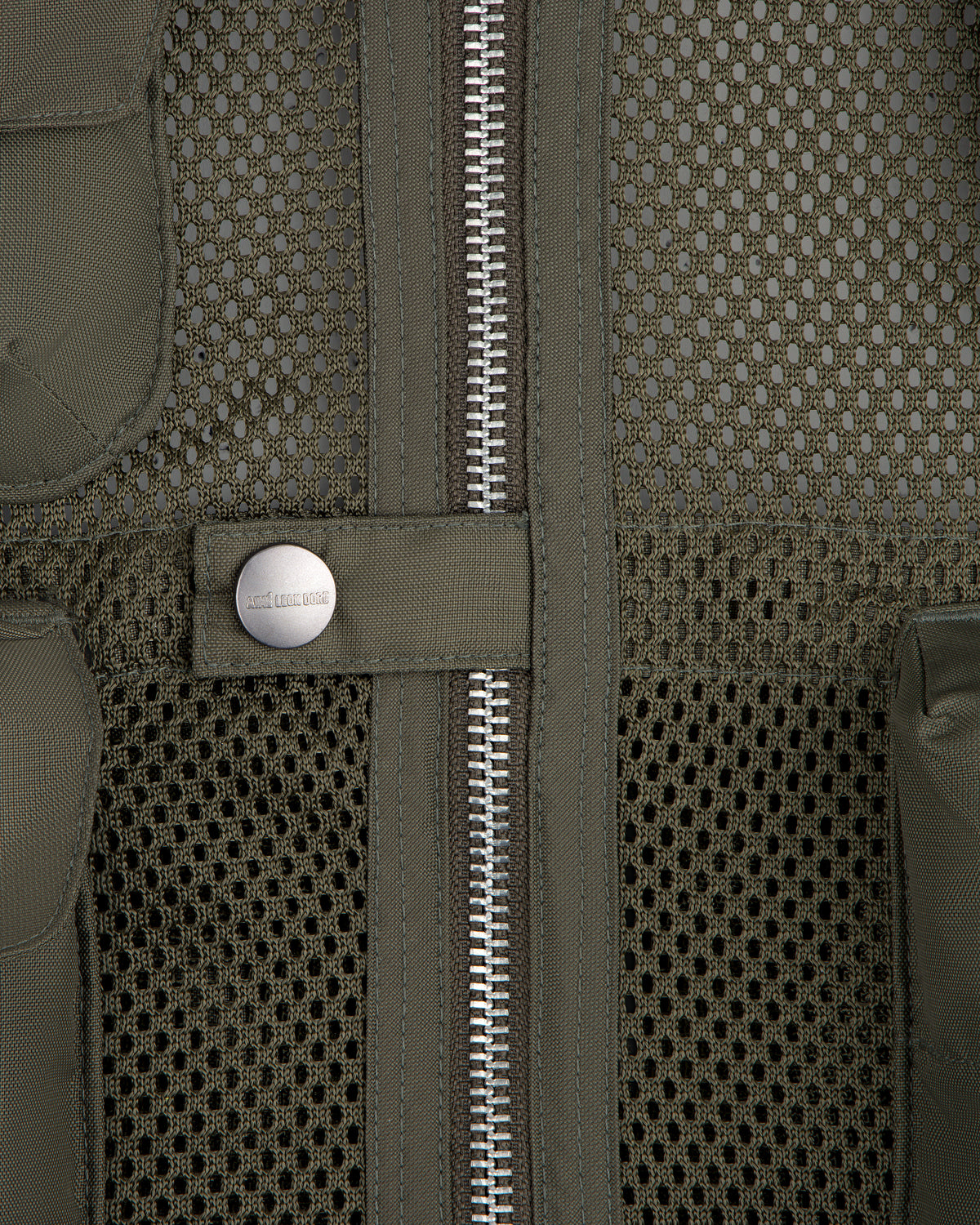 Close-up of the Nylon Utility Vest in olive green mesh, featuring a zipper and snap button pocket detail.