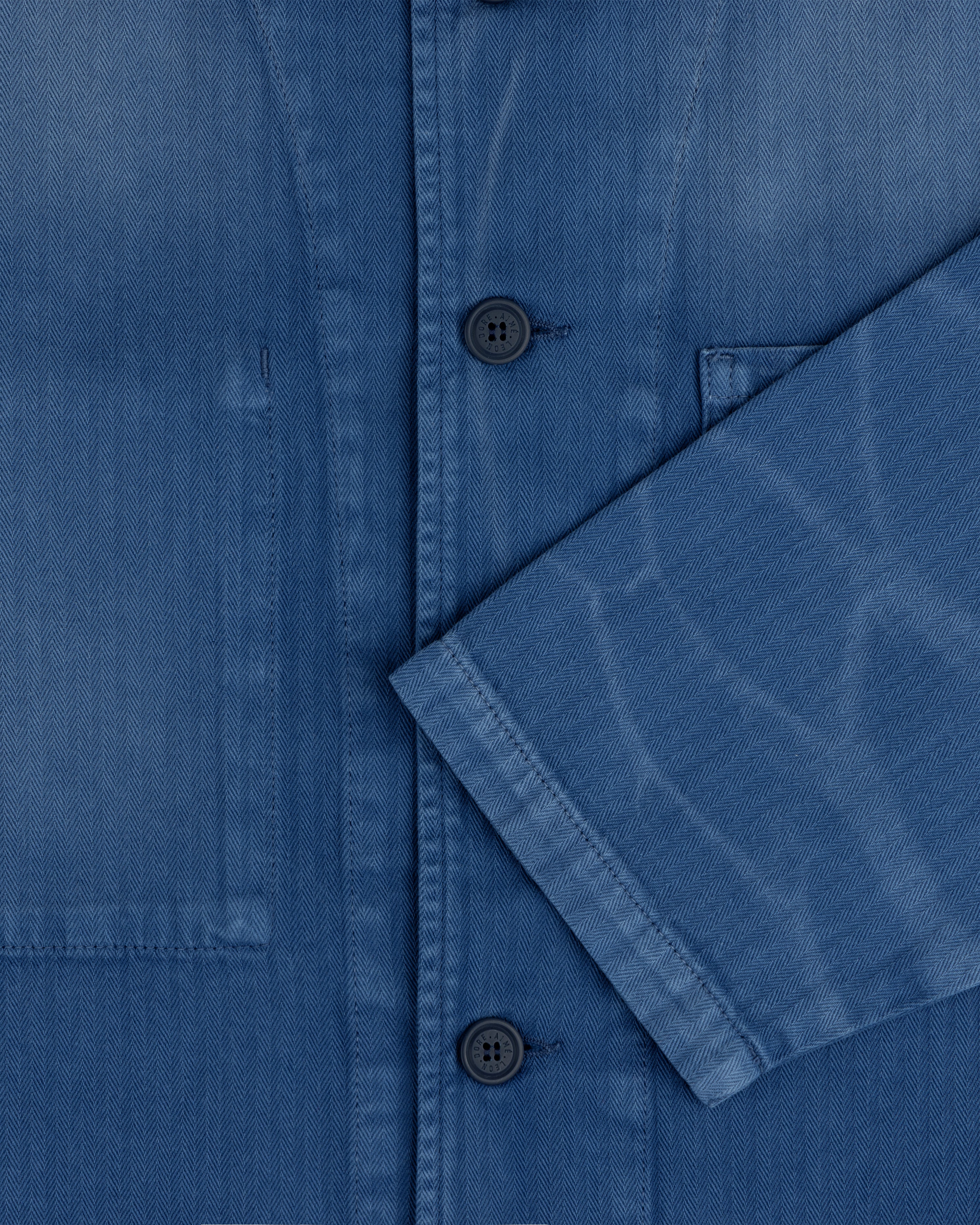 Close-up of the Sun Faded Chore Jacket in blue denim with black buttons, chest pocket, and folded sleeve detail.