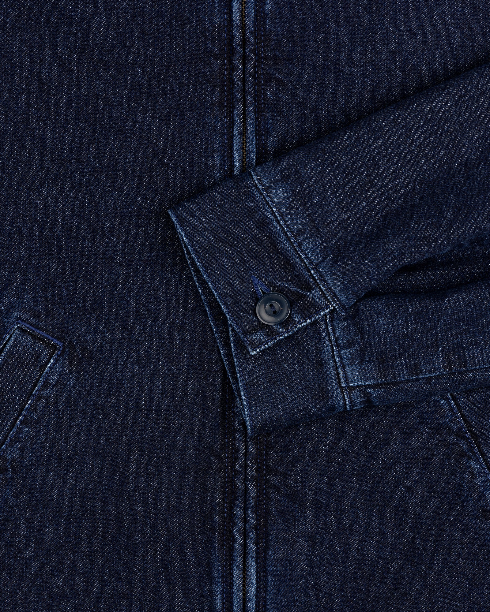 Close-up of a Denim Zip Jacket sleeve in dark blue with a buttoned cuff and visible pocket seams.
