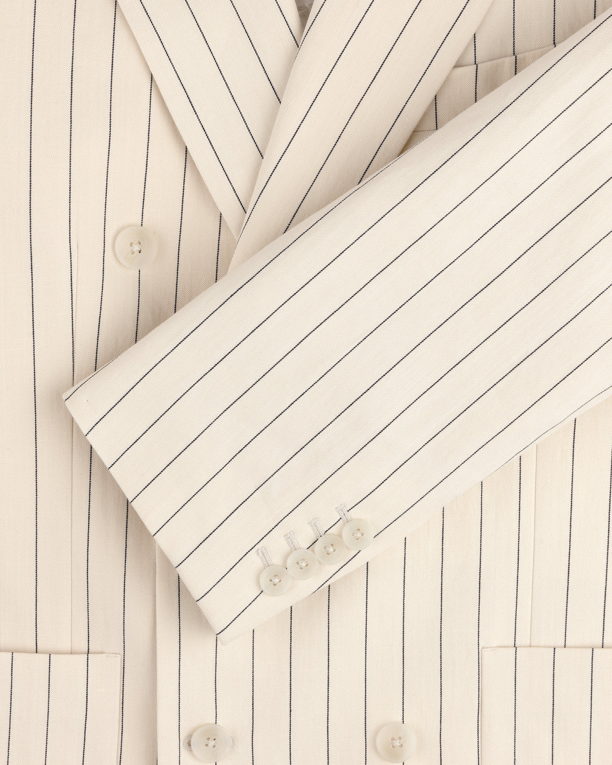 Close-up detail of the Double-Breasted Pinstripe Suit Jacket in cream with white buttons and notched lapel.