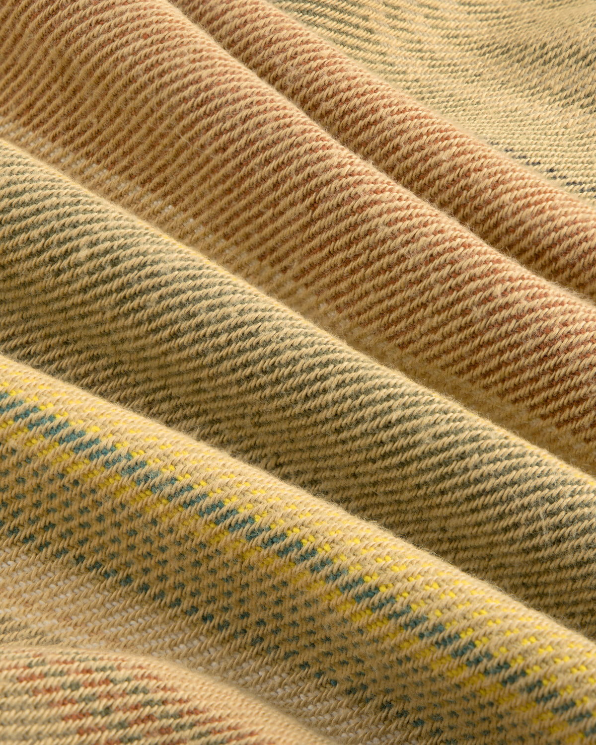 Close-up of the Blanket Striped Chore Jacket’s folded fabric in beige, yellow, and light brown woven diagonal stripes.