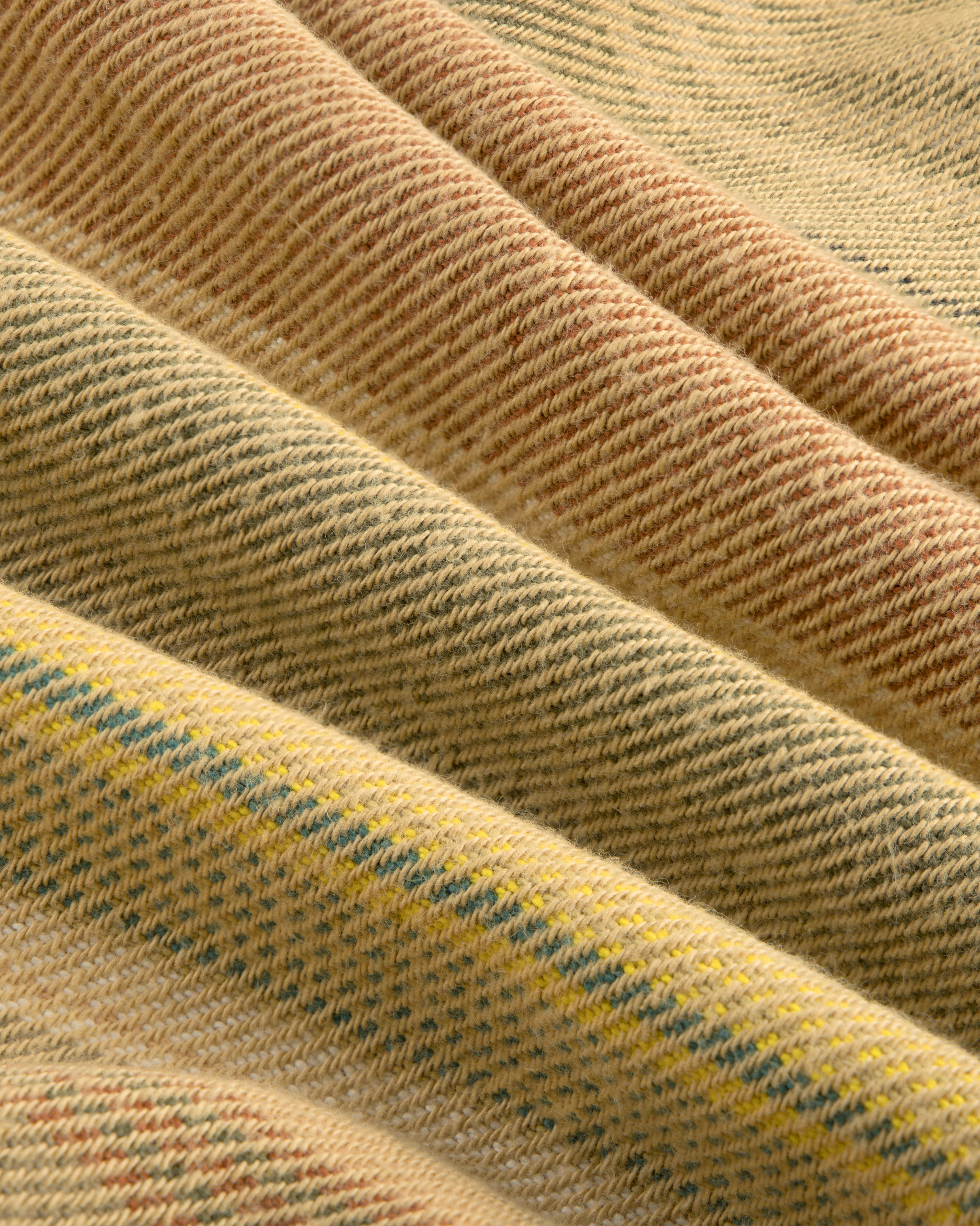 Close-up of the Blanket Striped Chore Jacket’s folded fabric in beige, yellow, and light brown woven diagonal stripes.