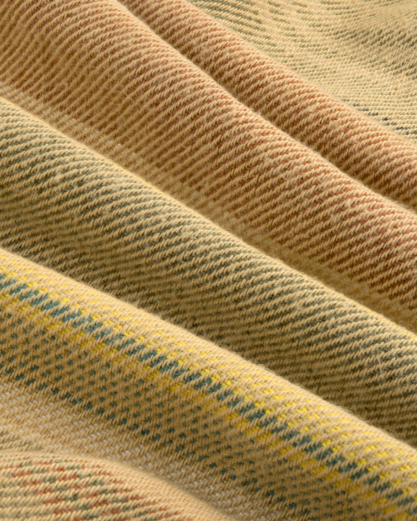 Close-up of the Blanket Striped Chore Jacket’s folded fabric in beige, yellow, and light brown woven diagonal stripes.