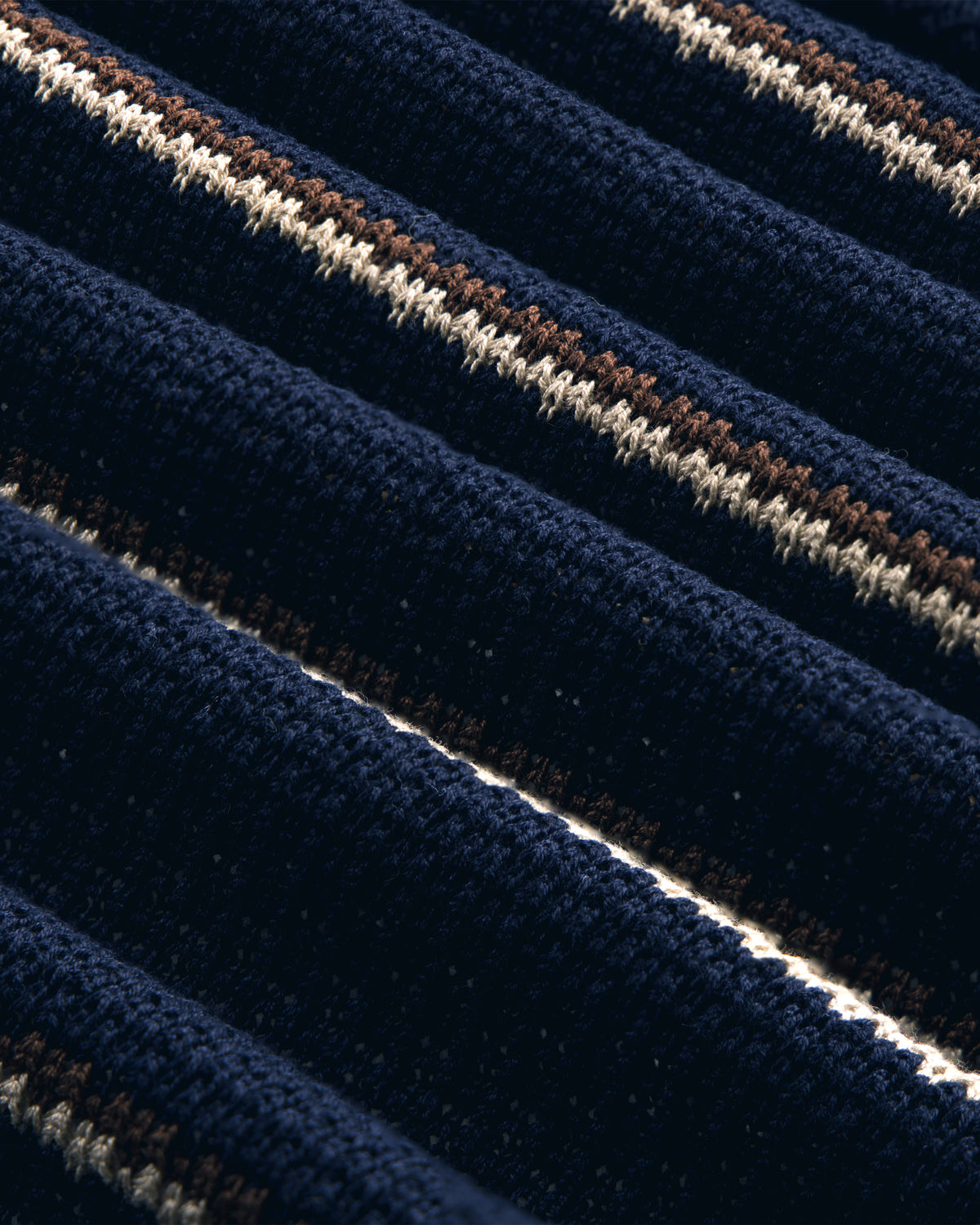 Close-up of the Striped Jacquard Shawl Collar Jacket in navy blue with white and brown ribbed stripes.