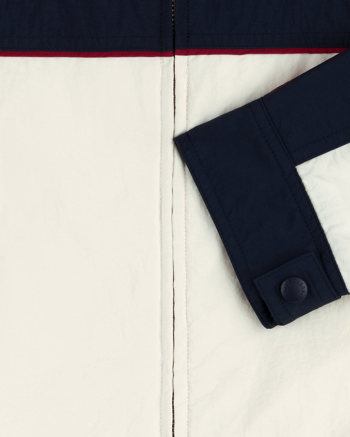 Close-up of the Nylon Moto Jacket with navy and off-white panels, a red accent, and a buttoned cuff.