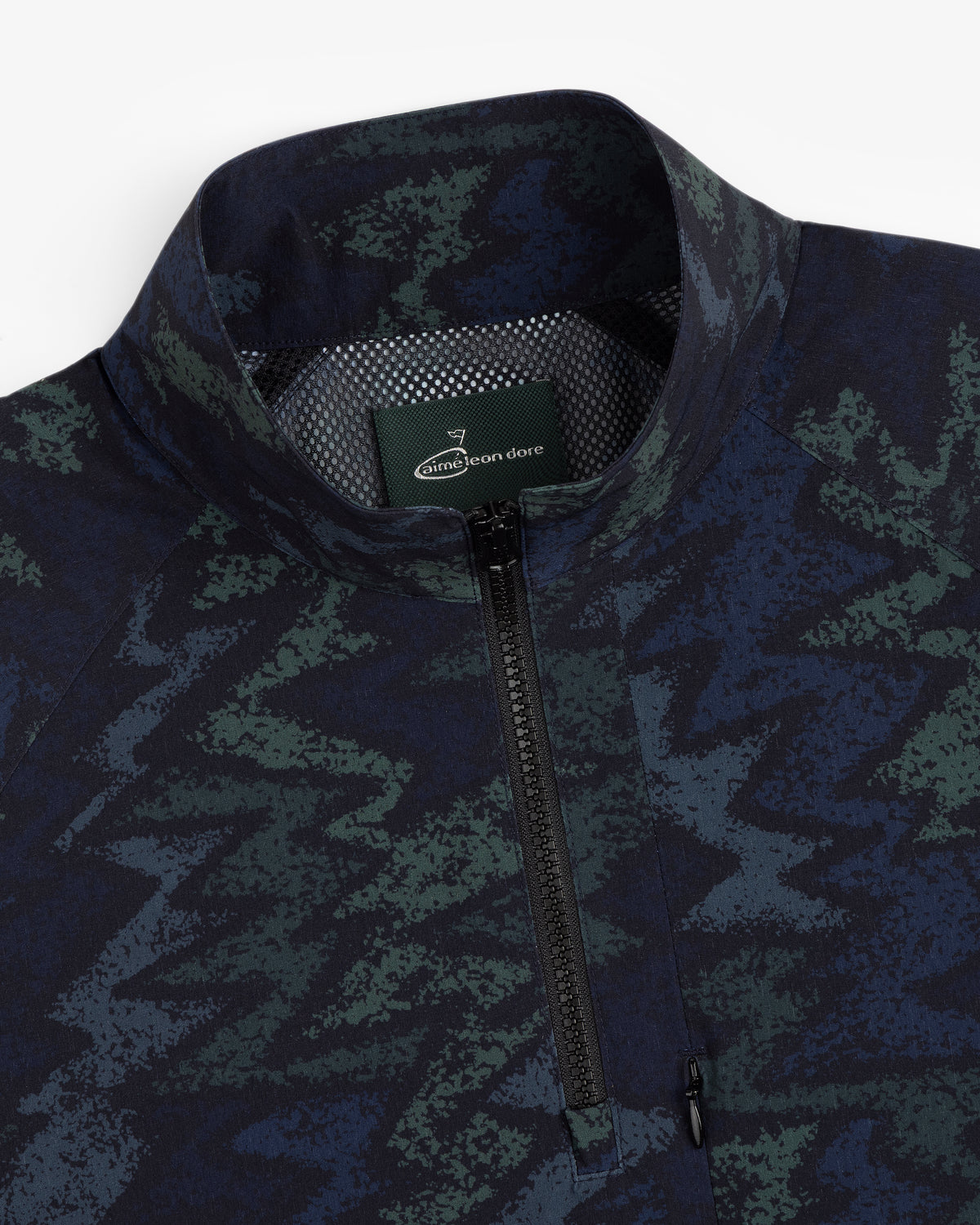 Close-up of an ALD Golf Nylon Quarter Zip Pullover with a green and blue zigzag pattern and Aimé Leon Dore collar label.