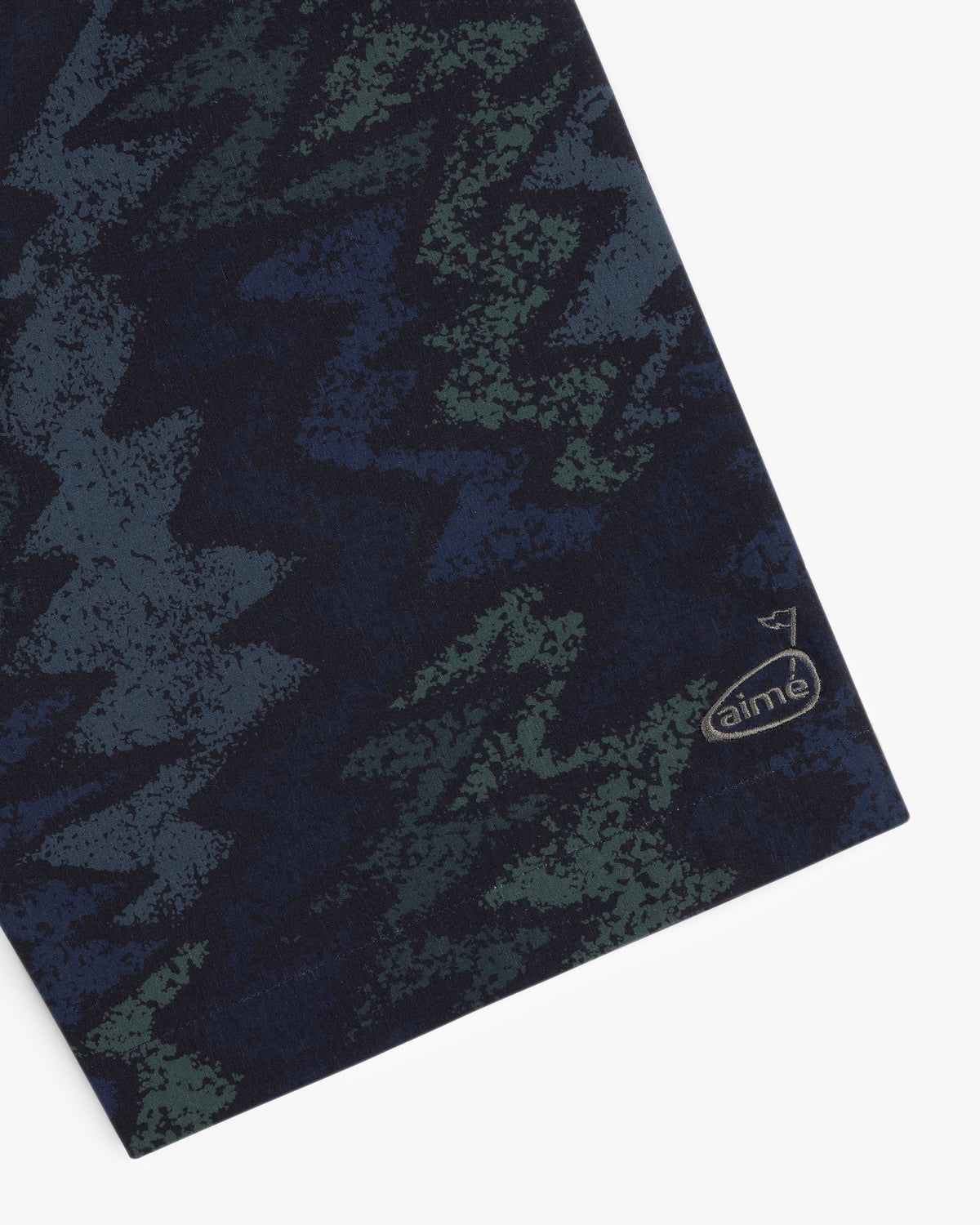 A close-up of the ALD Golf Nylon Quarter Zip Pullover with green and blue zigzag patterns and a small aimé logo.