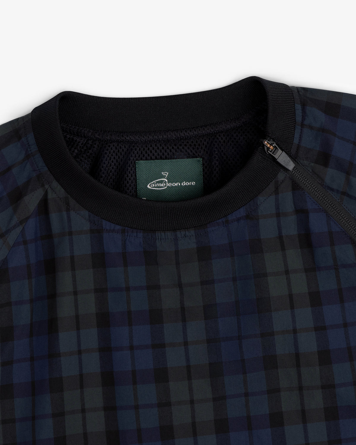 Close-up of the ALD Golf Blackwatch Pullover, featuring navy and black plaid with a black collar and Aimé Leon Dore label.