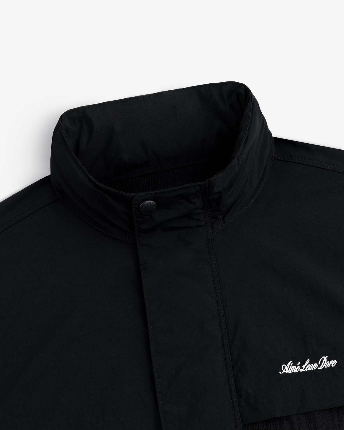 Close-up of a black Nylon Track Jacket with a high collar and "Aint-Lion-Dive" embroidered in white on the chest.