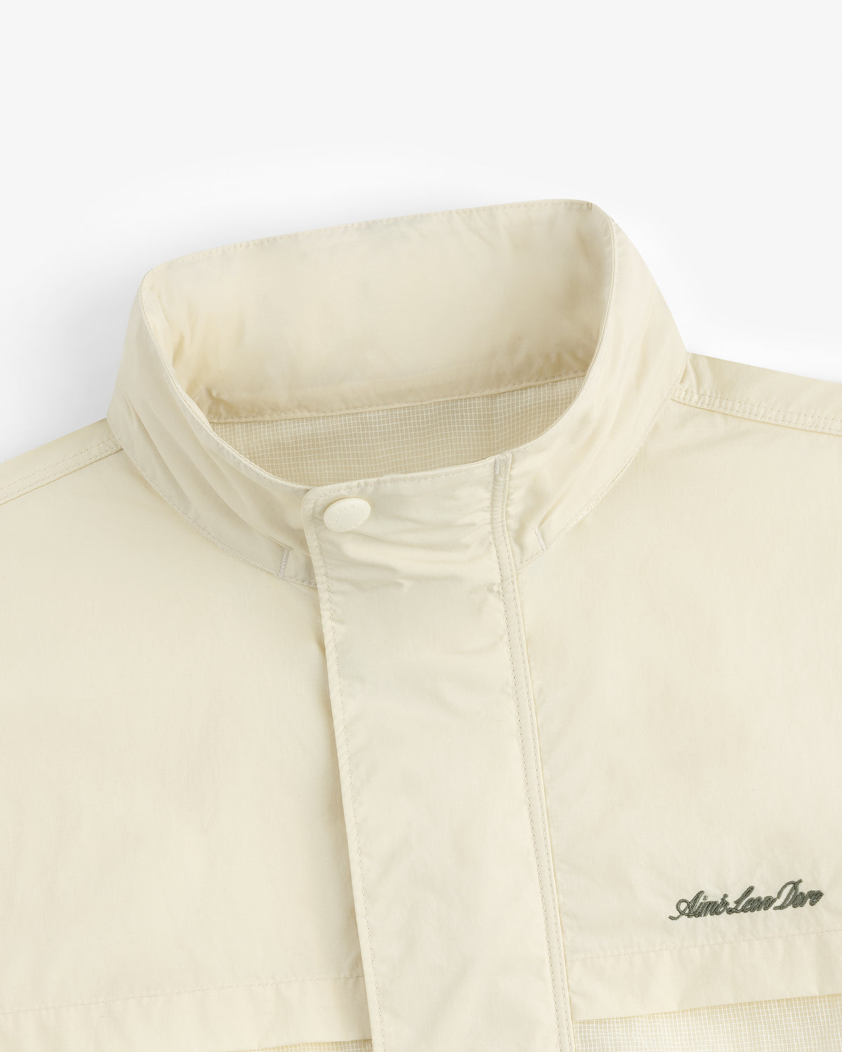 Close-up of the Nylon Track Jacket in cream, featuring a high collar and the Aimé Leon Dore logo embroidered on the chest.