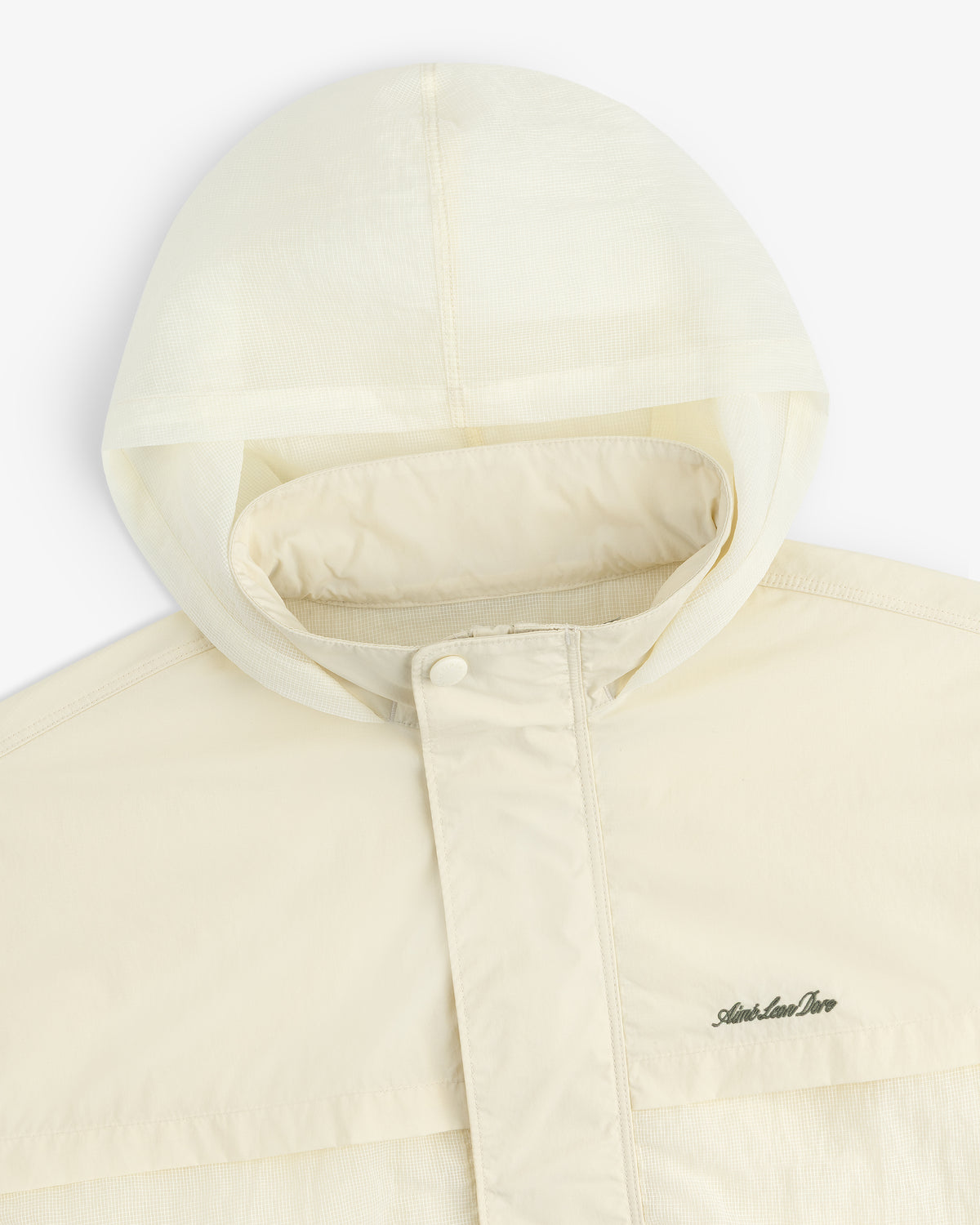 Cream nylon track jacket with hood, snap-button flap, and subtle embroidered chest logo.