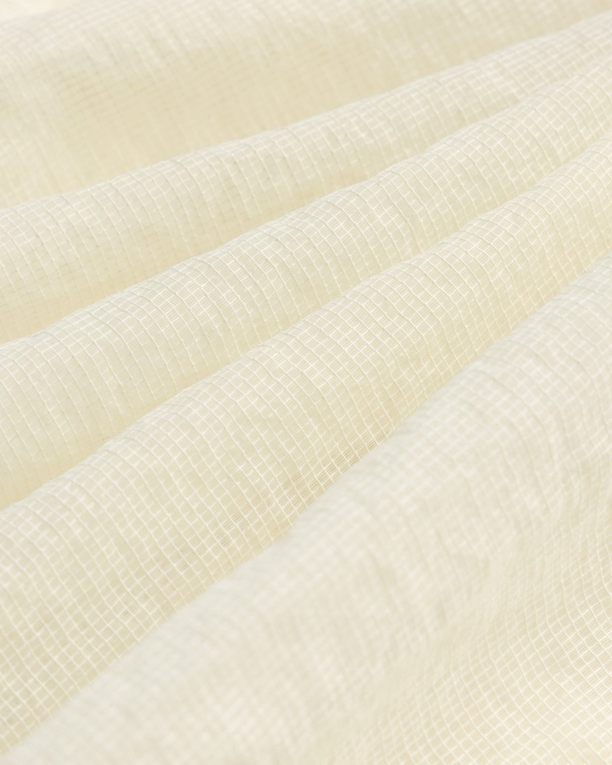 Close-up of the Nylon Track Jacket's white, textured fabric featuring a subtle grid pattern and gentle folds.