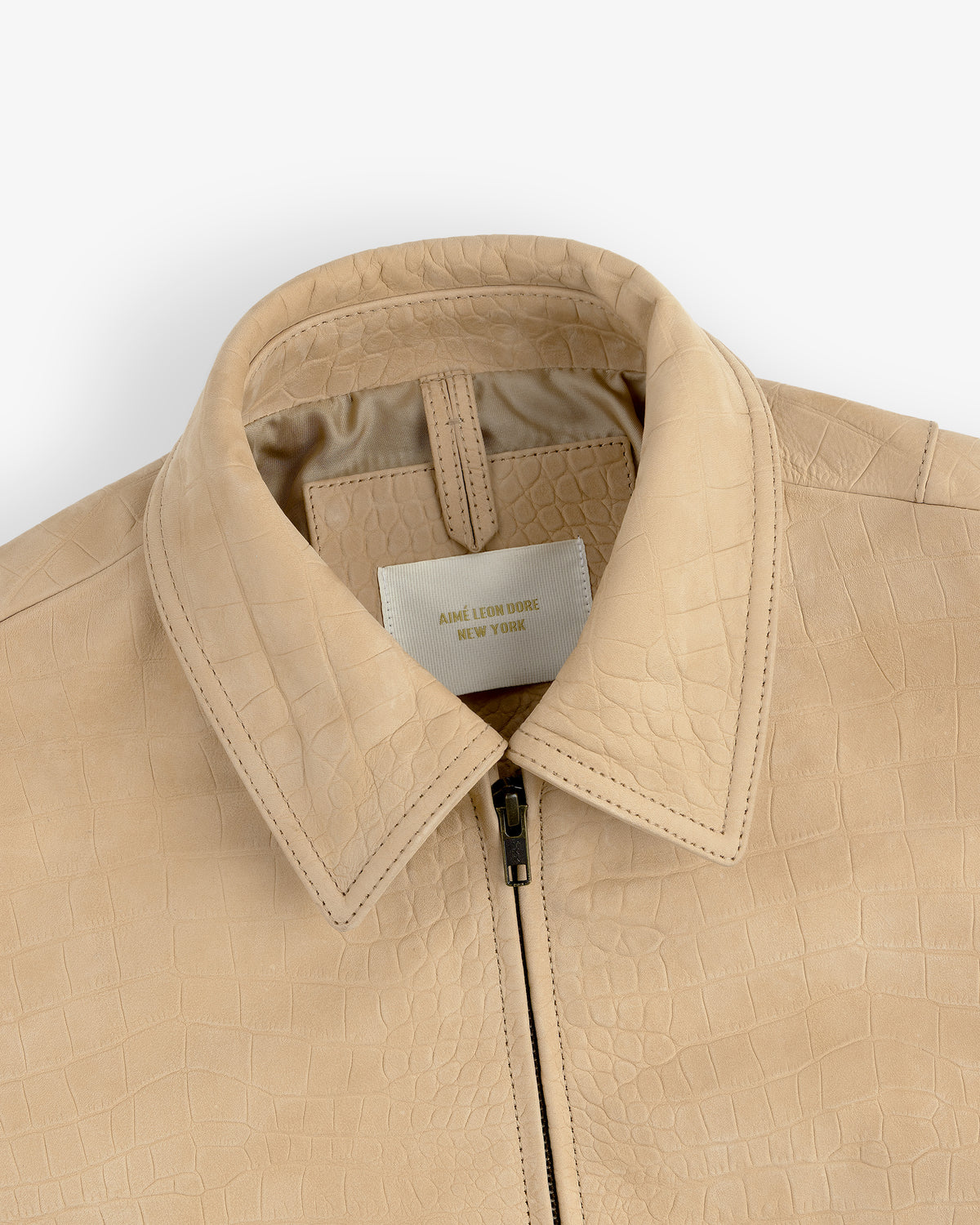 Close-up of a Croc-Embossed Nubuck Bomber Jacket with zipper and visible label inside the collar.