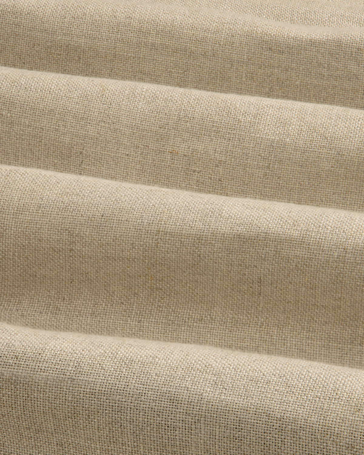 The Linen Trench Coat features beige, textured fabric with horizontal, wavy folds for a dynamic light and shadow effect.