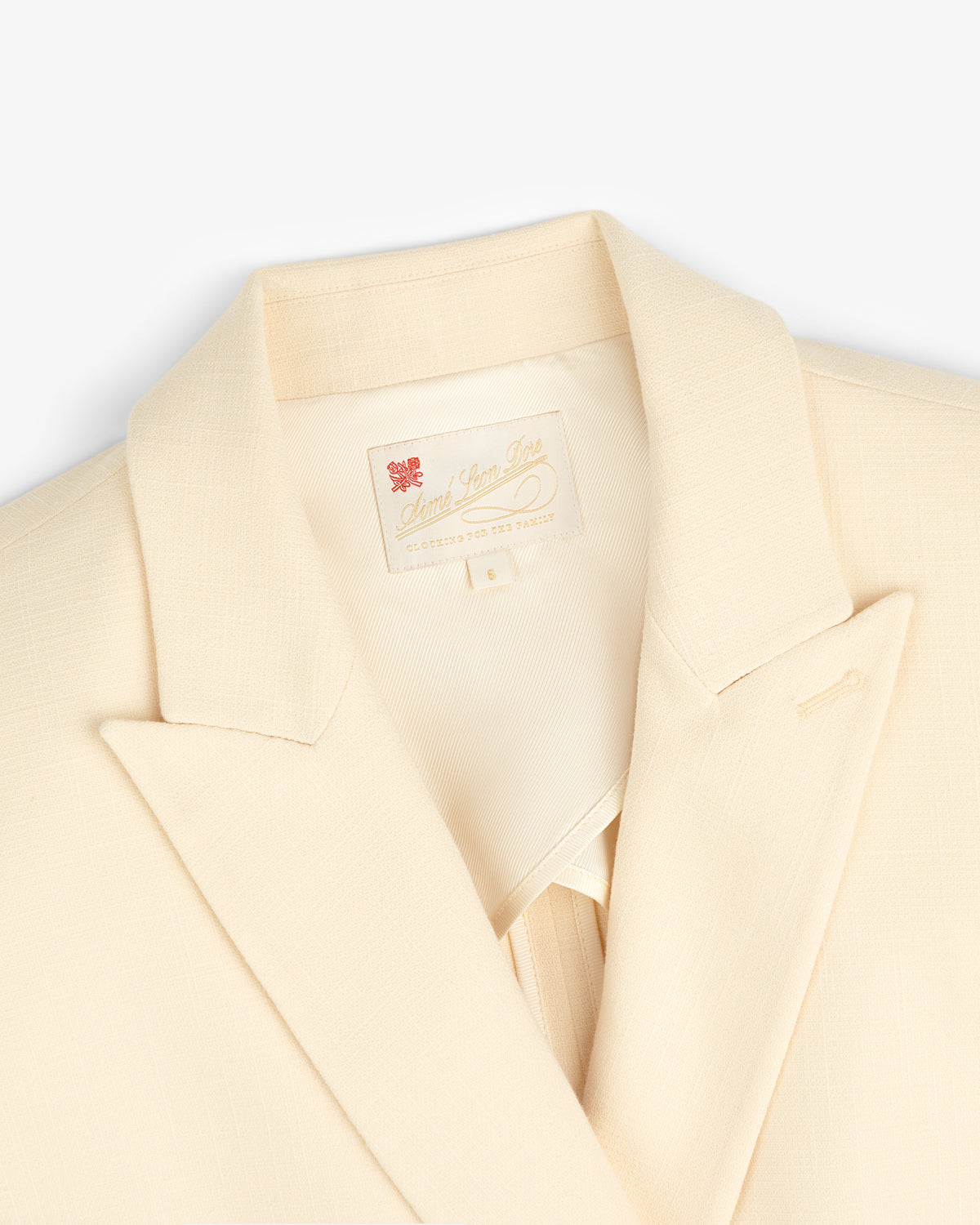 Close-up of the Double-Breasted Unconstructed Blazer in cream with notched lapel and sewn-in collar label.