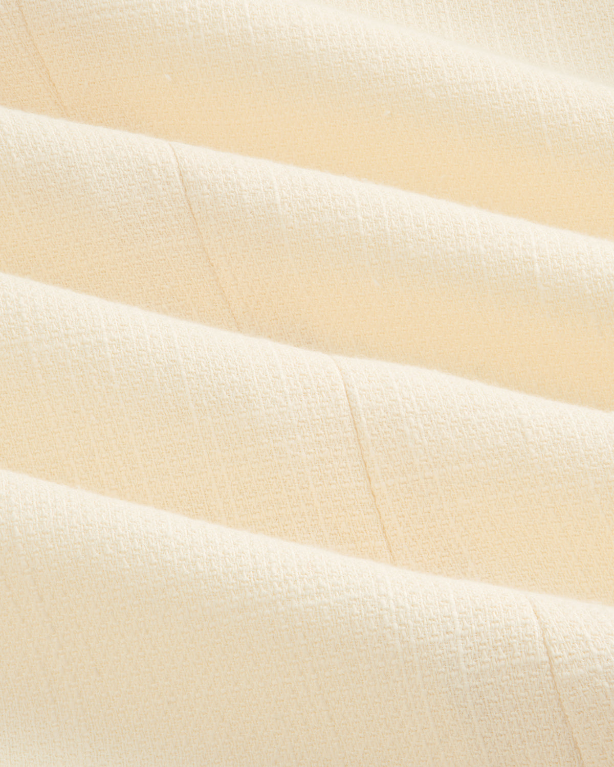 Close-up of cream-colored textured fabric with subtle grid pattern on a Double-Breasted Unconstructed Blazer.