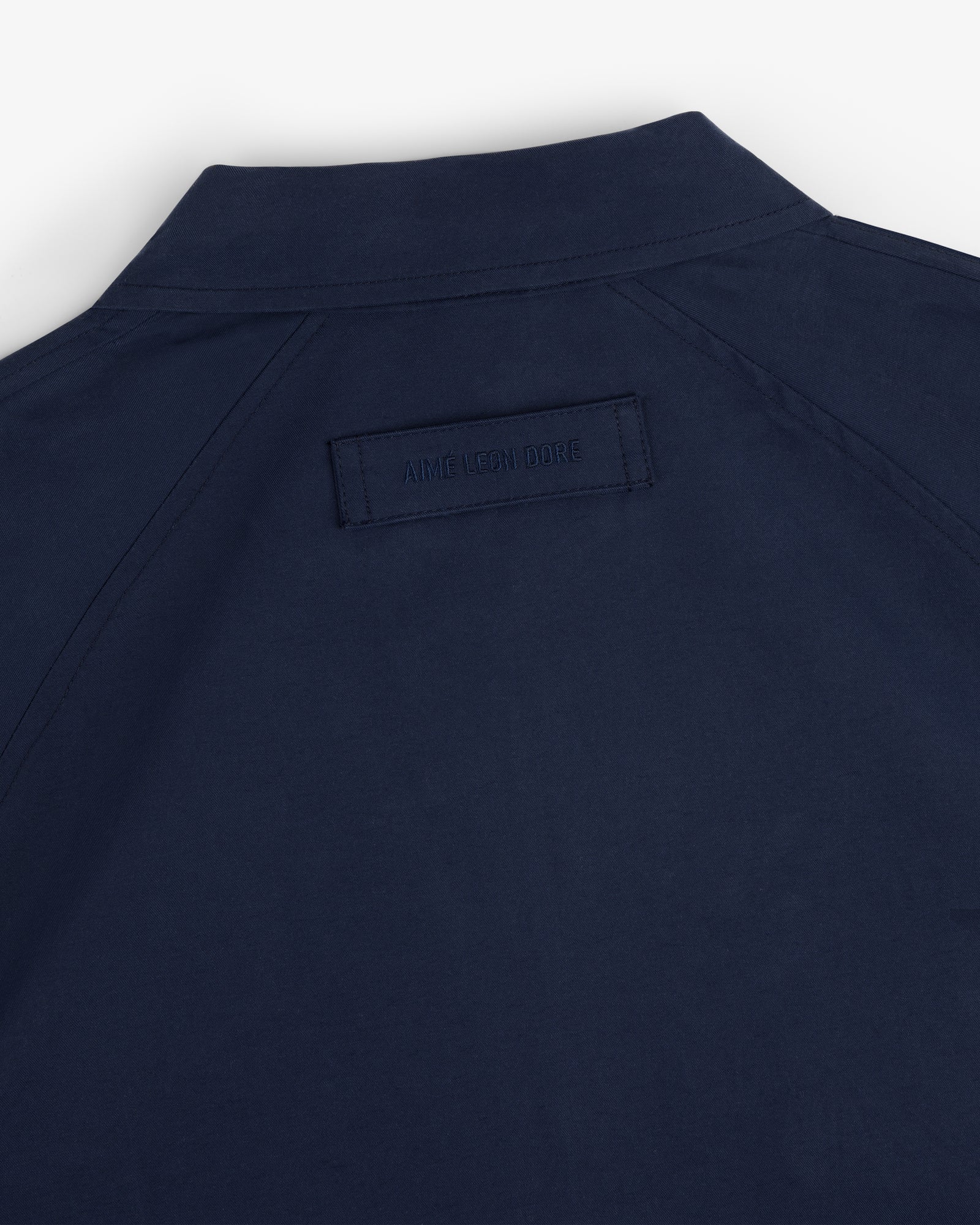 Navy Crest Casual Jacket with a collar and rectangular AIME LEON DORE label stitched on the upper back.