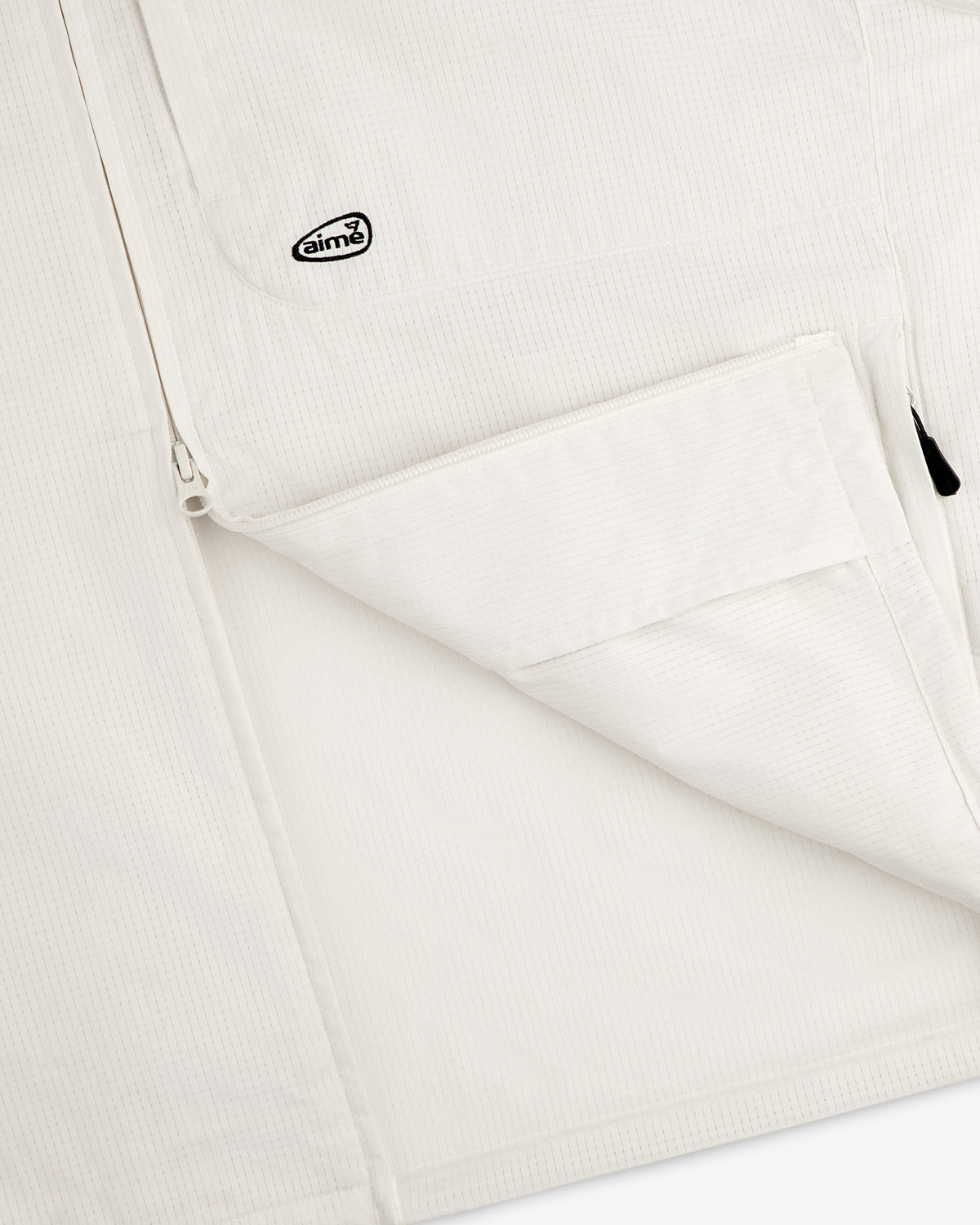 Close-up of the ALD Golf Lightweight Tips Windbreaker, featuring a zip pocket and small Aimé logo patch near the zipper.