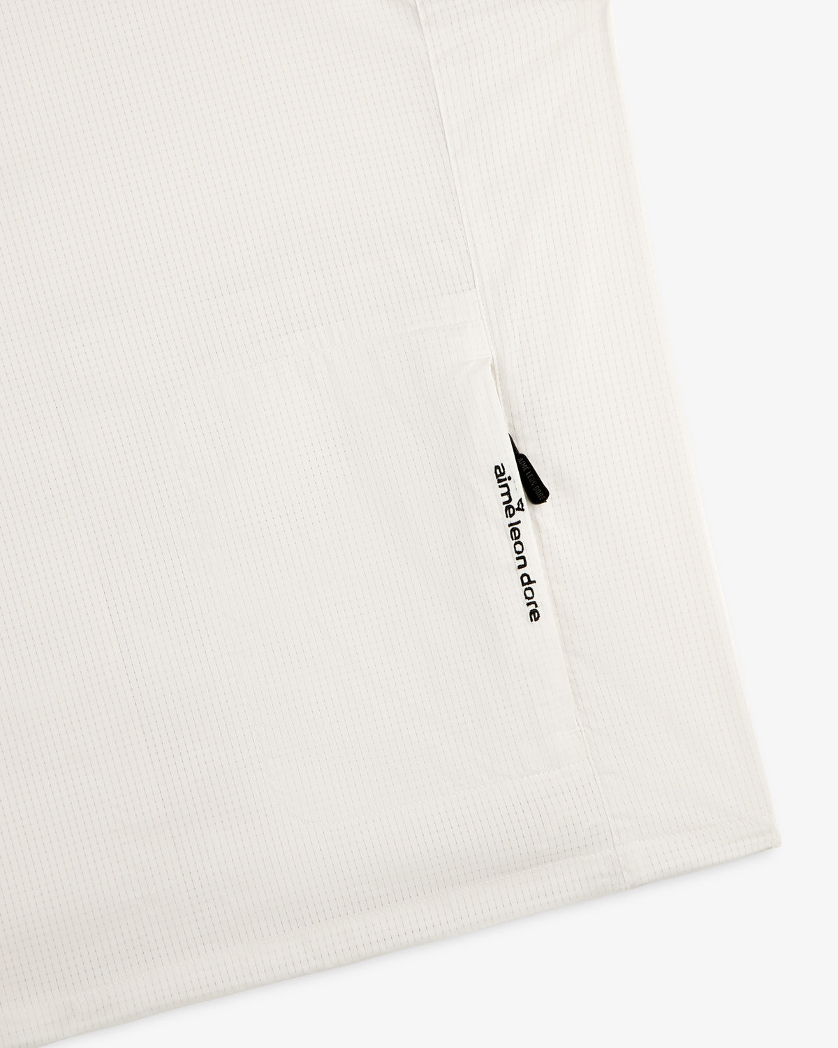 White textured ALD Golf Lightweight Tips Windbreaker with a small vertical zipper pocket and aimé leon dore text.