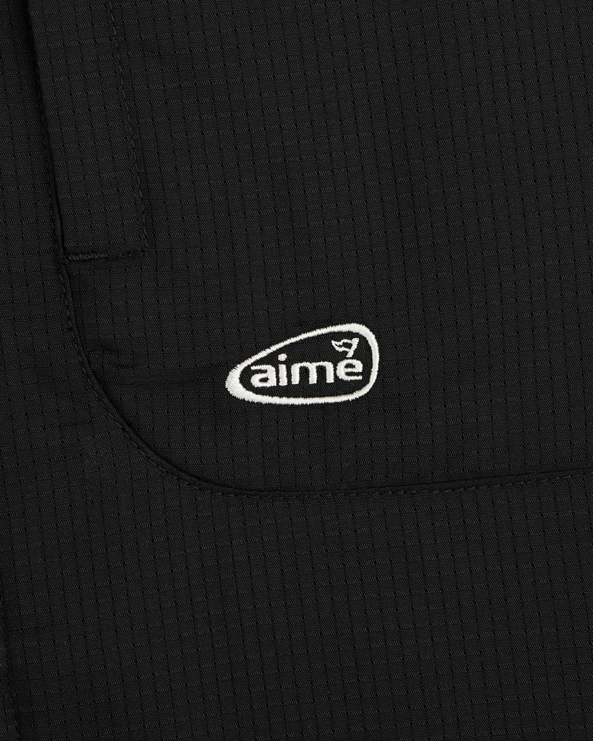 Black textured fabric ALD Golf Lightweight Tips Windbreaker with small white aime logo embroidered on pocket.