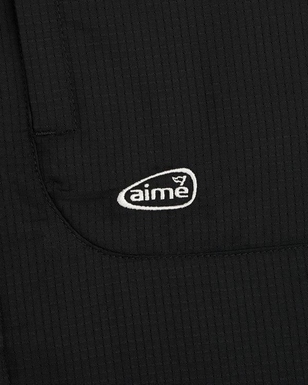 Black textured fabric ALD Golf Lightweight Tips Windbreaker with small white aime logo embroidered on pocket.